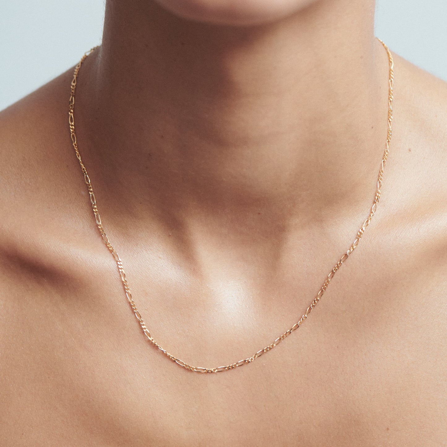 Elegant gold chain necklace on a woman's neck; luxury minimalist jewellery showcased against a soft background.