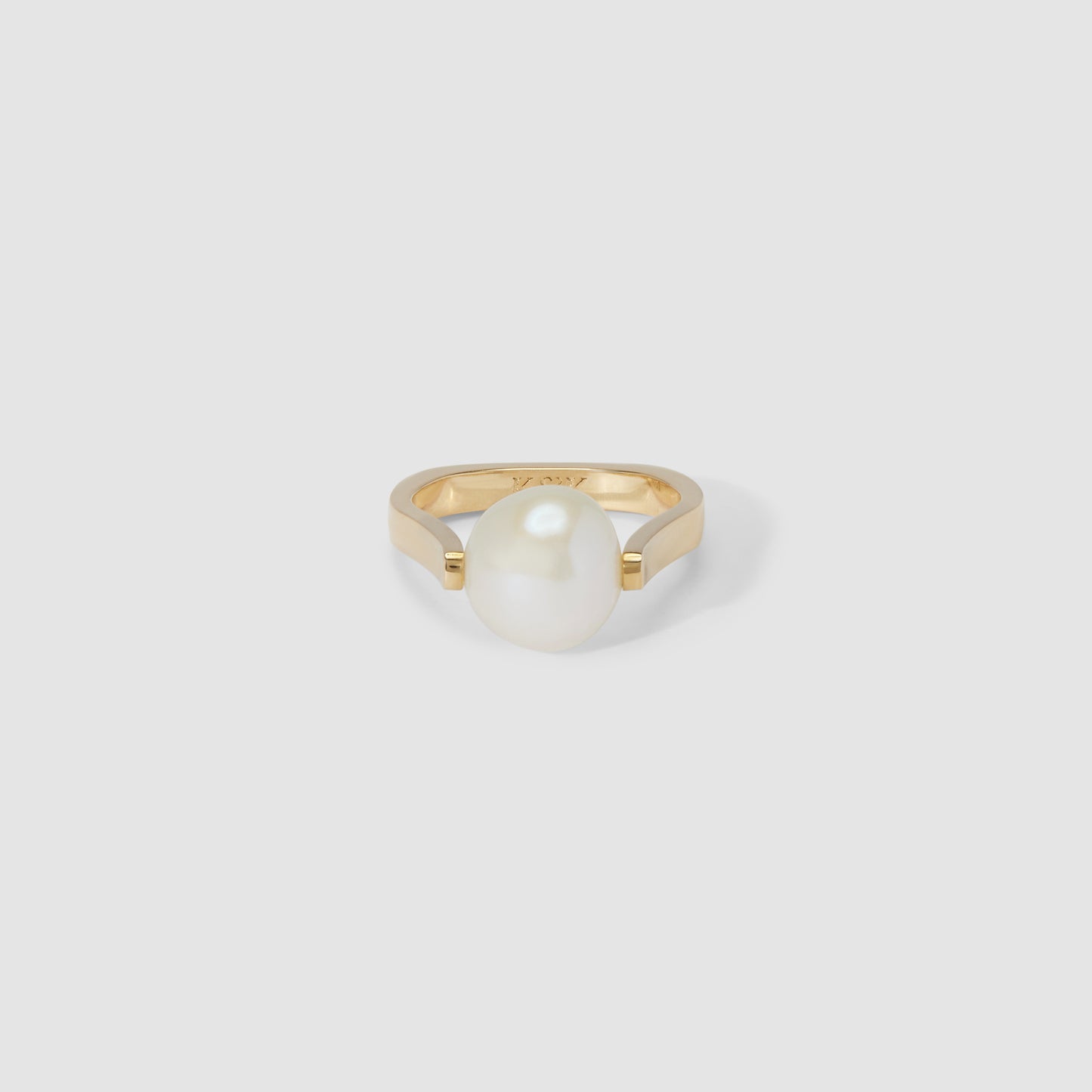Gold ring featuring a single large pearl, set against a plain grey background. Luxurious and elegant jewellery design.