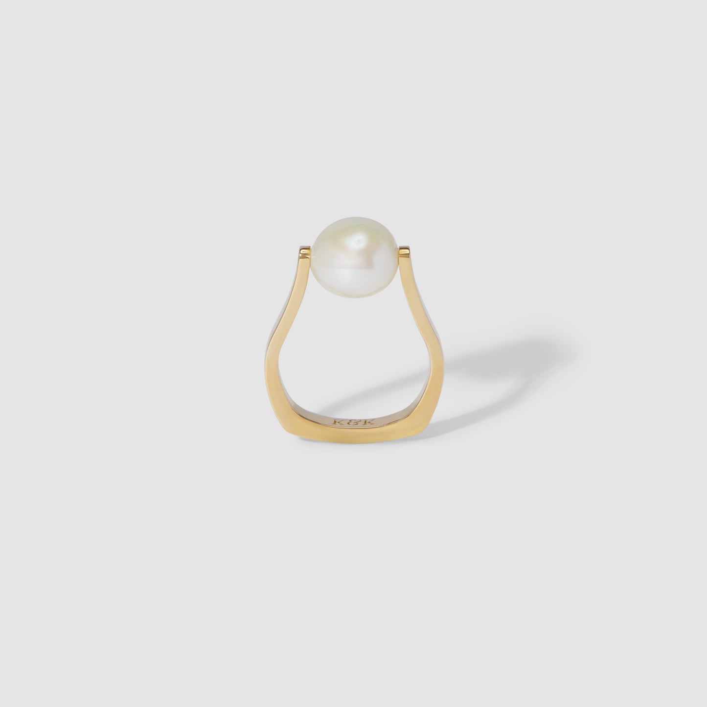 Gold ring with a modern open band design, featuring a single white pearl, set against a plain grey background. Perfect for luxury jewellery lovers.