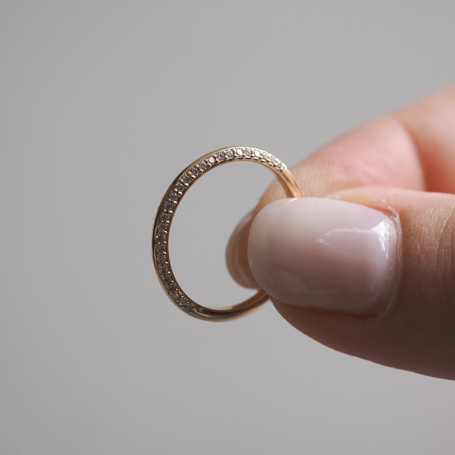 Hand holding an elegant gold ring with small diamonds, showcasing luxury jewellery craftsmanship. Perfect for high-end jewellery enthusiasts.