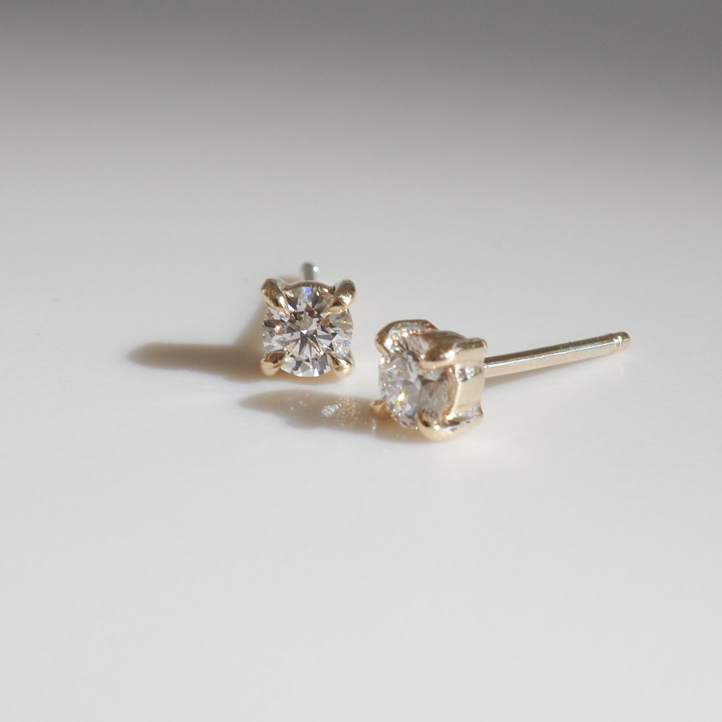 Gold diamond stud earrings on a white surface, showcasing elegance and luxury jewellery design.