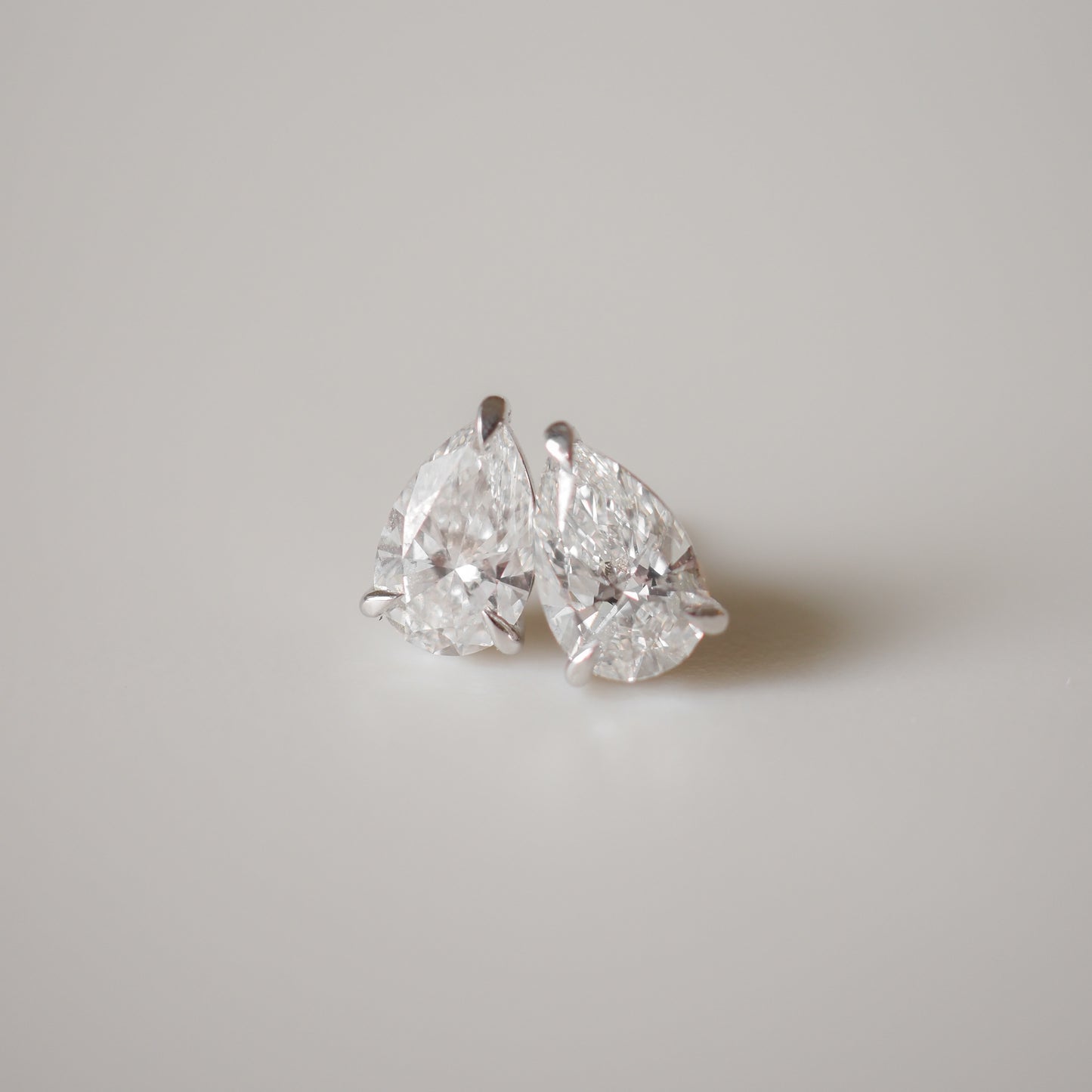 Two sparkling pear-shaped diamonds on a soft grey background, showcasing their clarity and elegance. Perfect for luxury jewellery lovers.