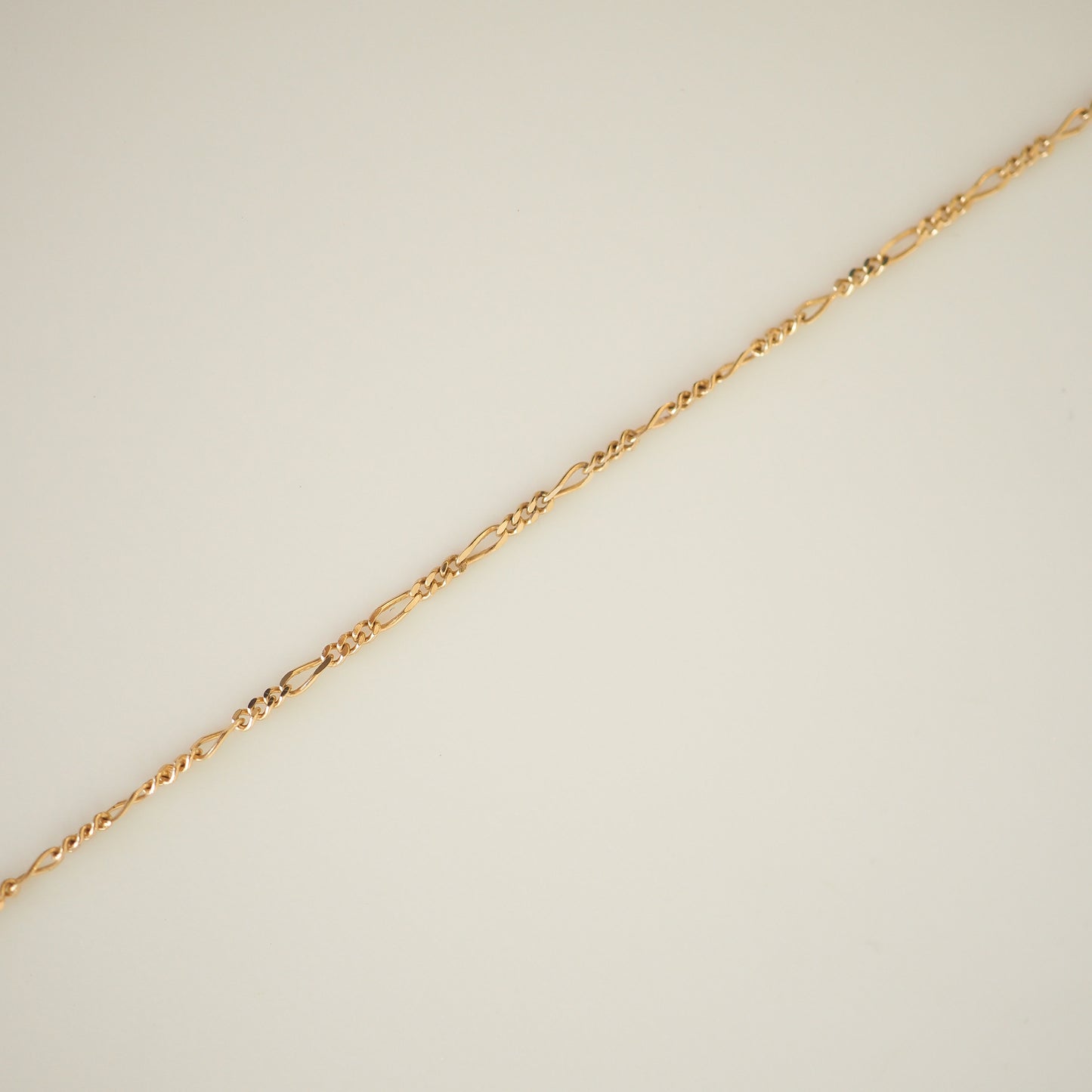 Elegant gold twist chain necklace displayed on a light background, showcasing intricate design and luxury craftsmanship.