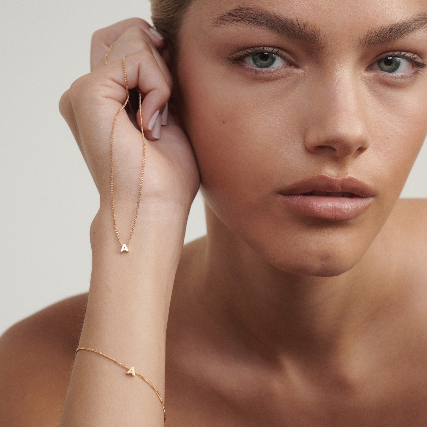 Woman wearing gold jewelry with a plain background