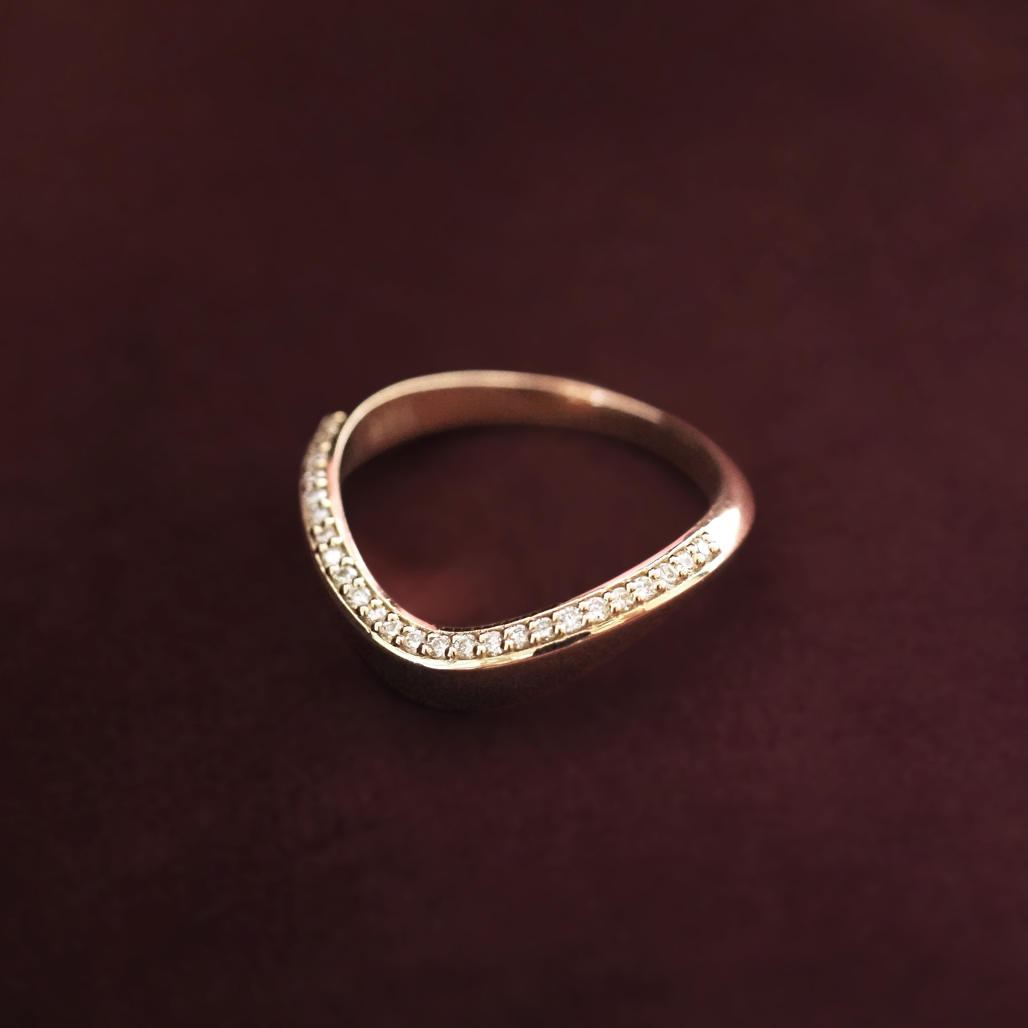 Gold ring with small diamonds on a dark brown background