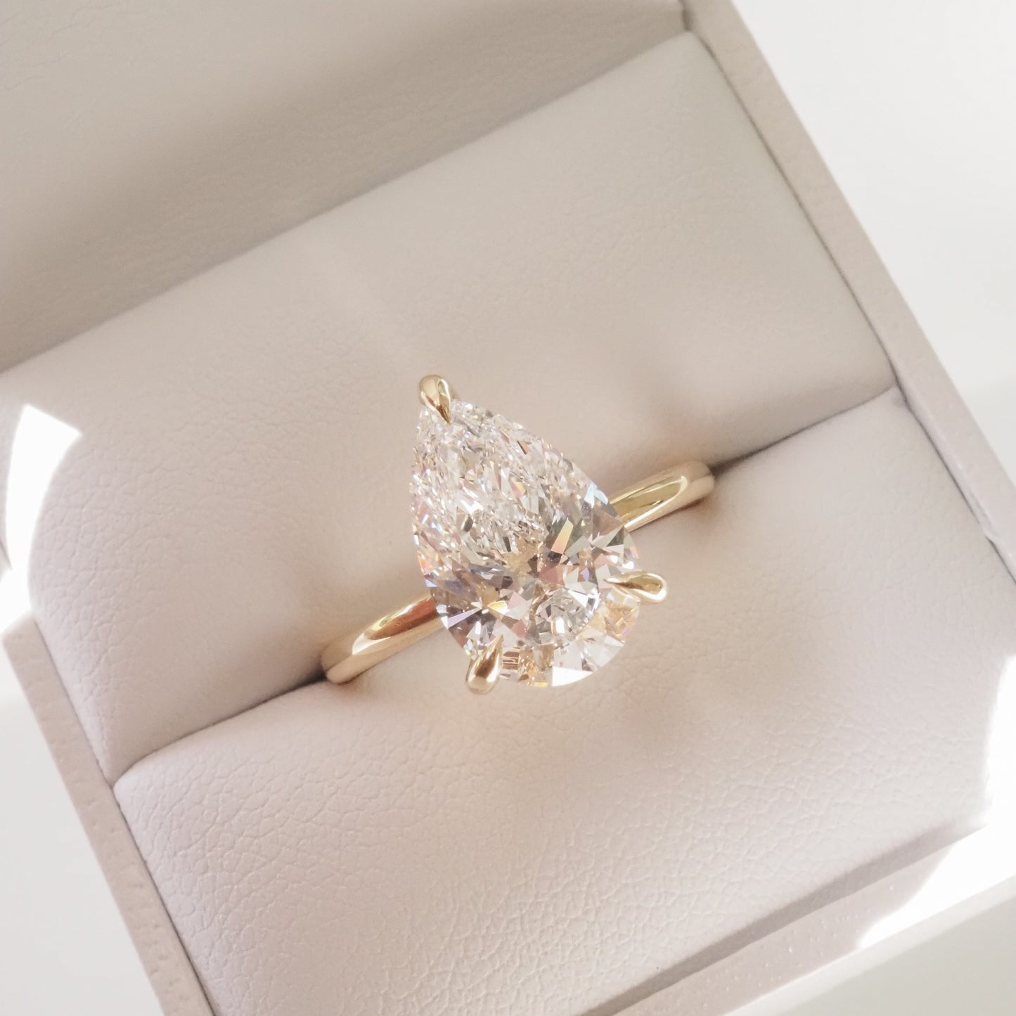 Gold ring featuring a pear-shaped diamond in an elegant jewellery box, capturing luxury and sophistication.