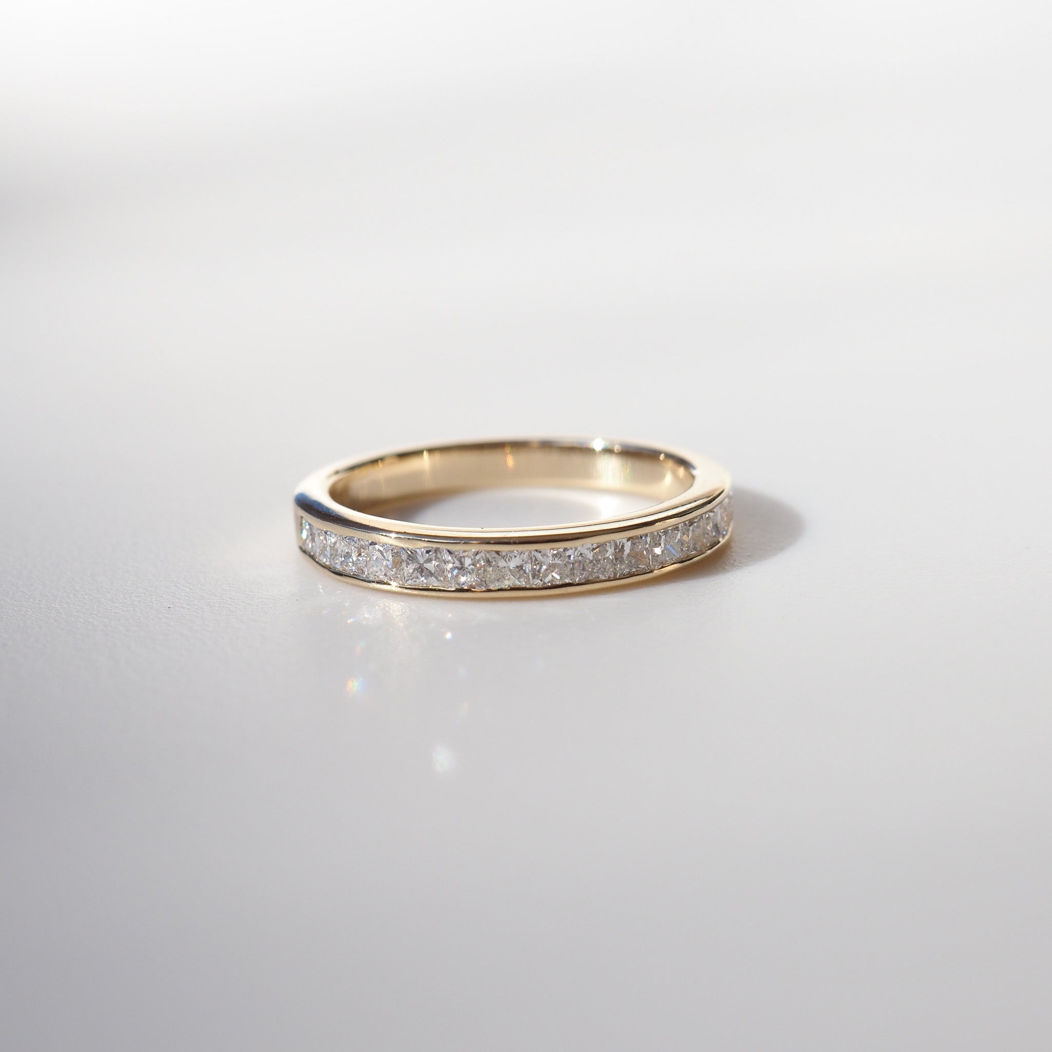 Gold band with embedded diamonds, elegantly displayed on a light background, showcasing luxury jewellery craftsmanship.