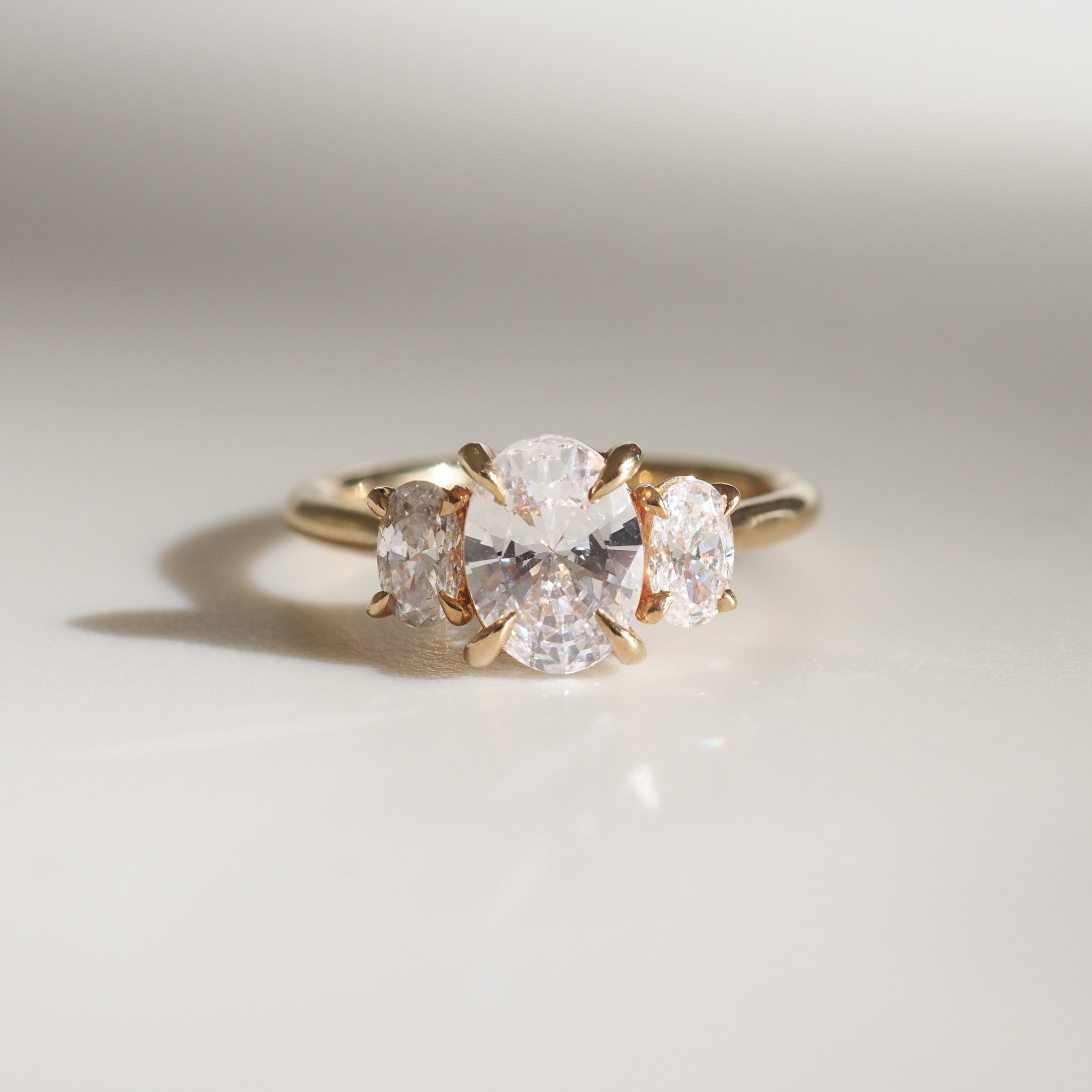 Gold ring with three oval-cut diamonds, elegantly set on a polished surface, capturing refined luxury and sophistication in fine jewellery design.