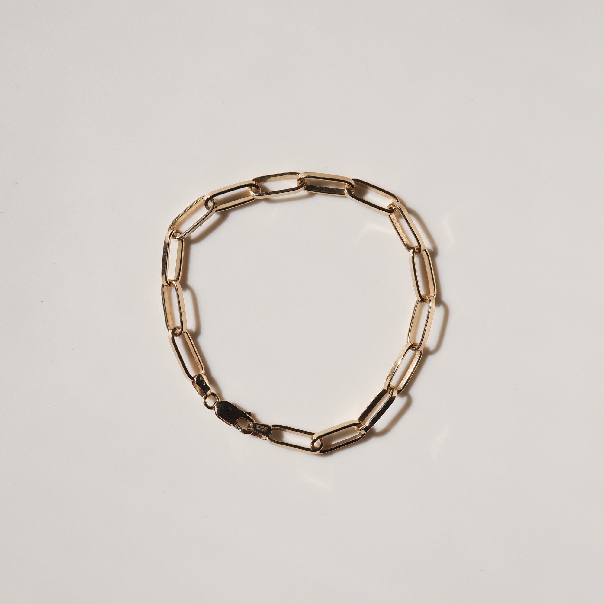 Gold link chain bracelet on a minimalist light background, showcasing luxury jewellery craftsmanship.