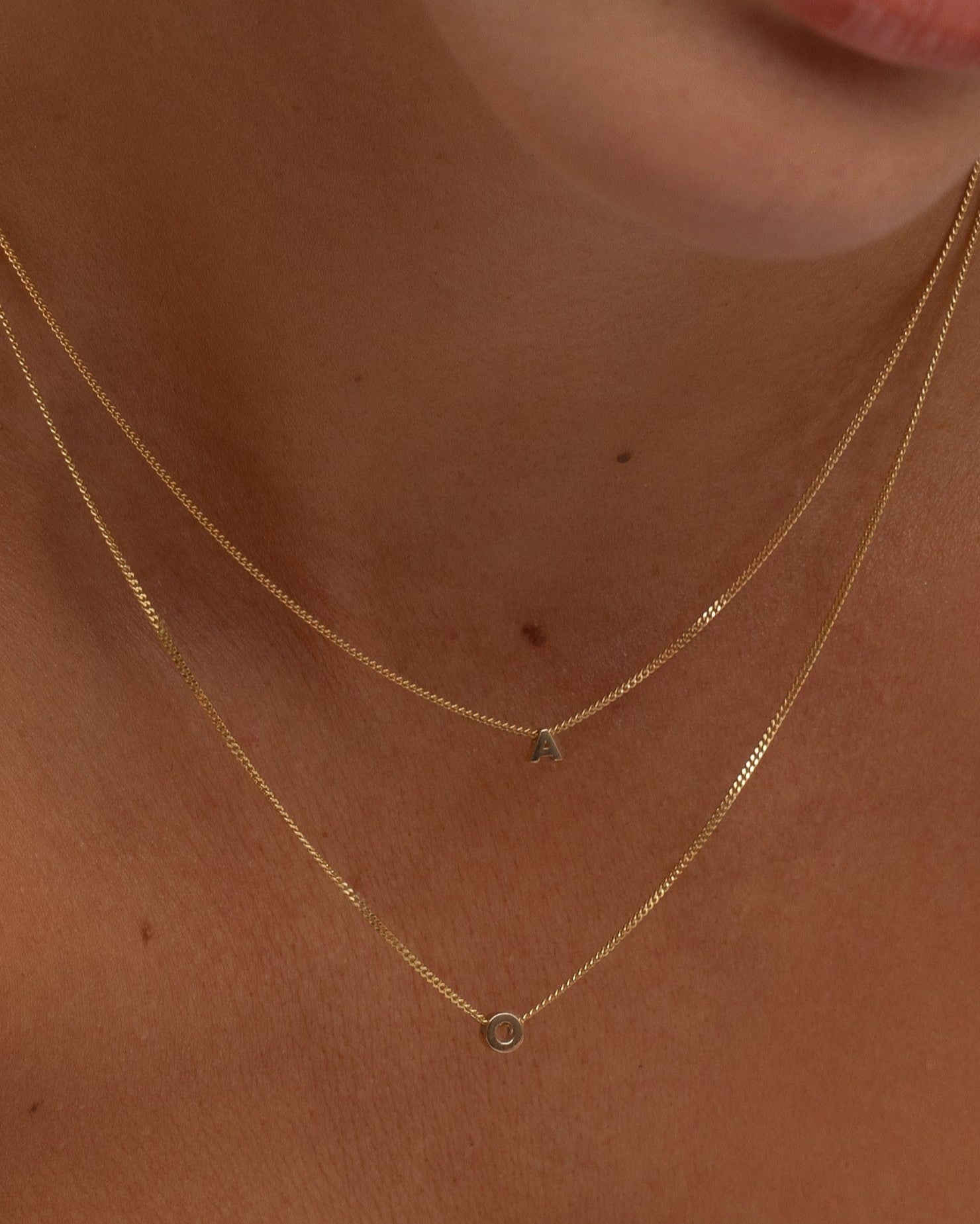 Close-up of a person wearing a delicate gold necklace with small pendants.