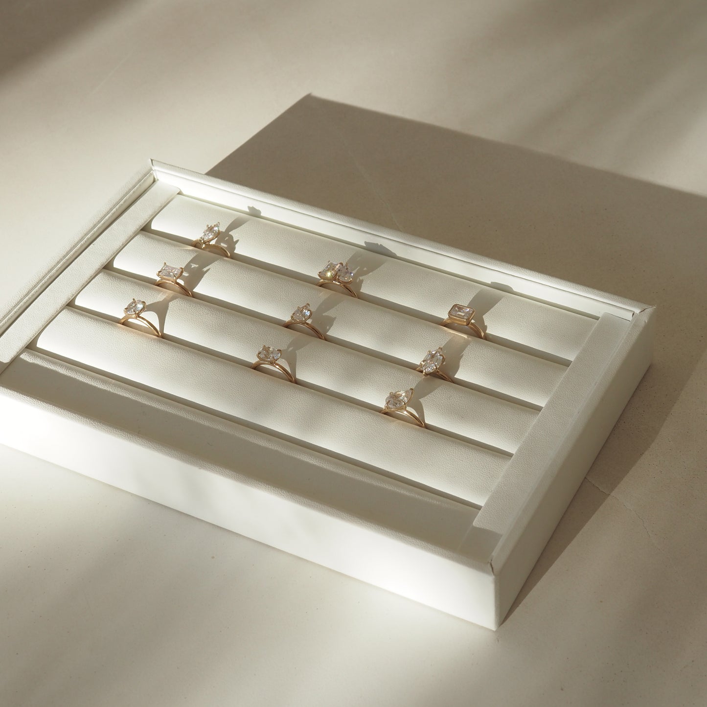 A collection of elegant gold rings with large gemstones, displayed in a white jewellery box under soft lighting. Perfect for luxury ring shopping.