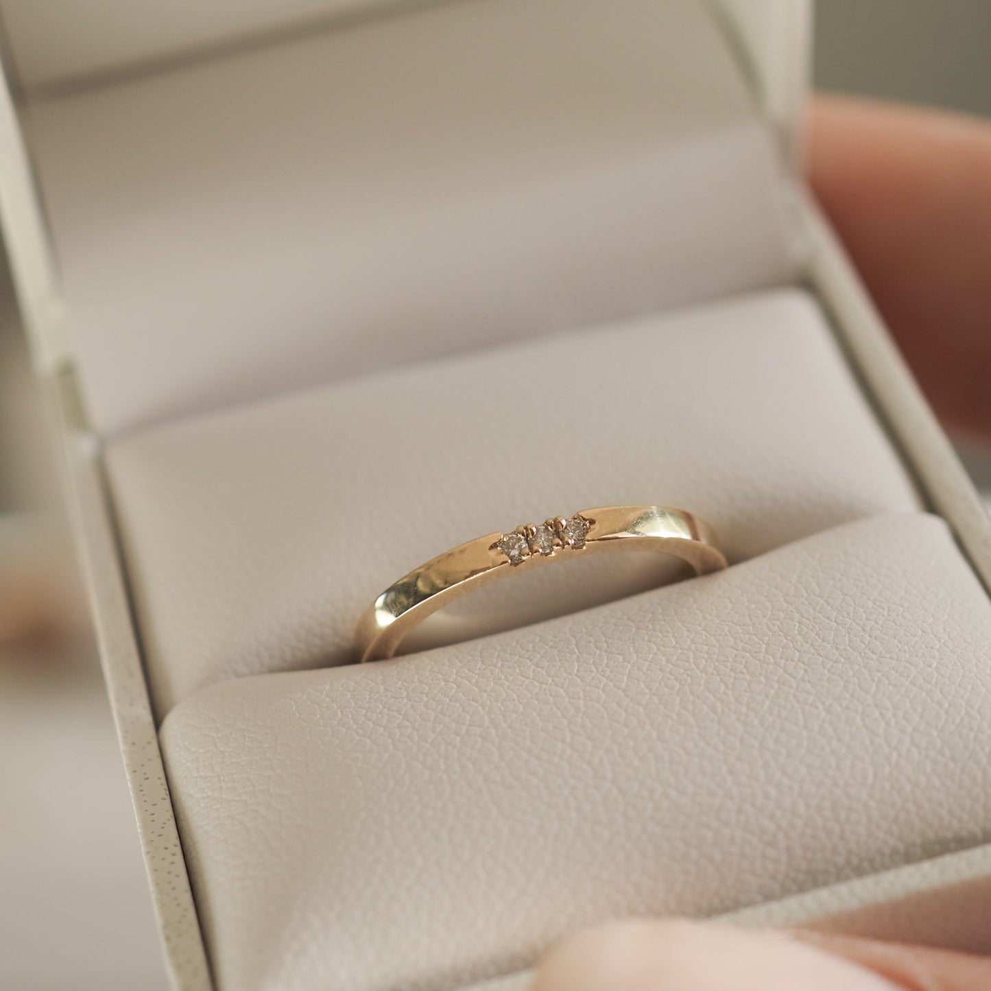Gold ring with small diamond accents displayed in an open jewellery box. Elegant design, perfect for luxury engagement or wedding bands.