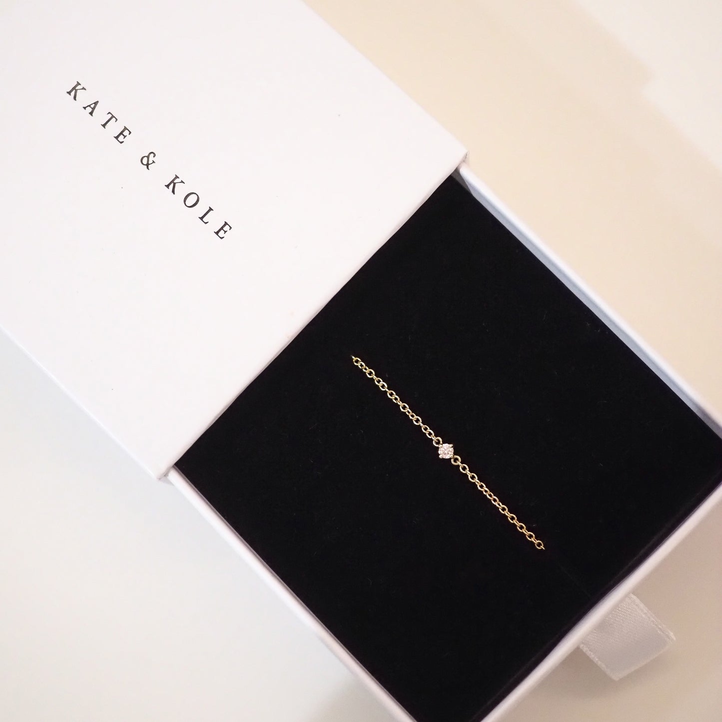 Gold bracelet in a 'KATE & KOLE' branded box on a light background