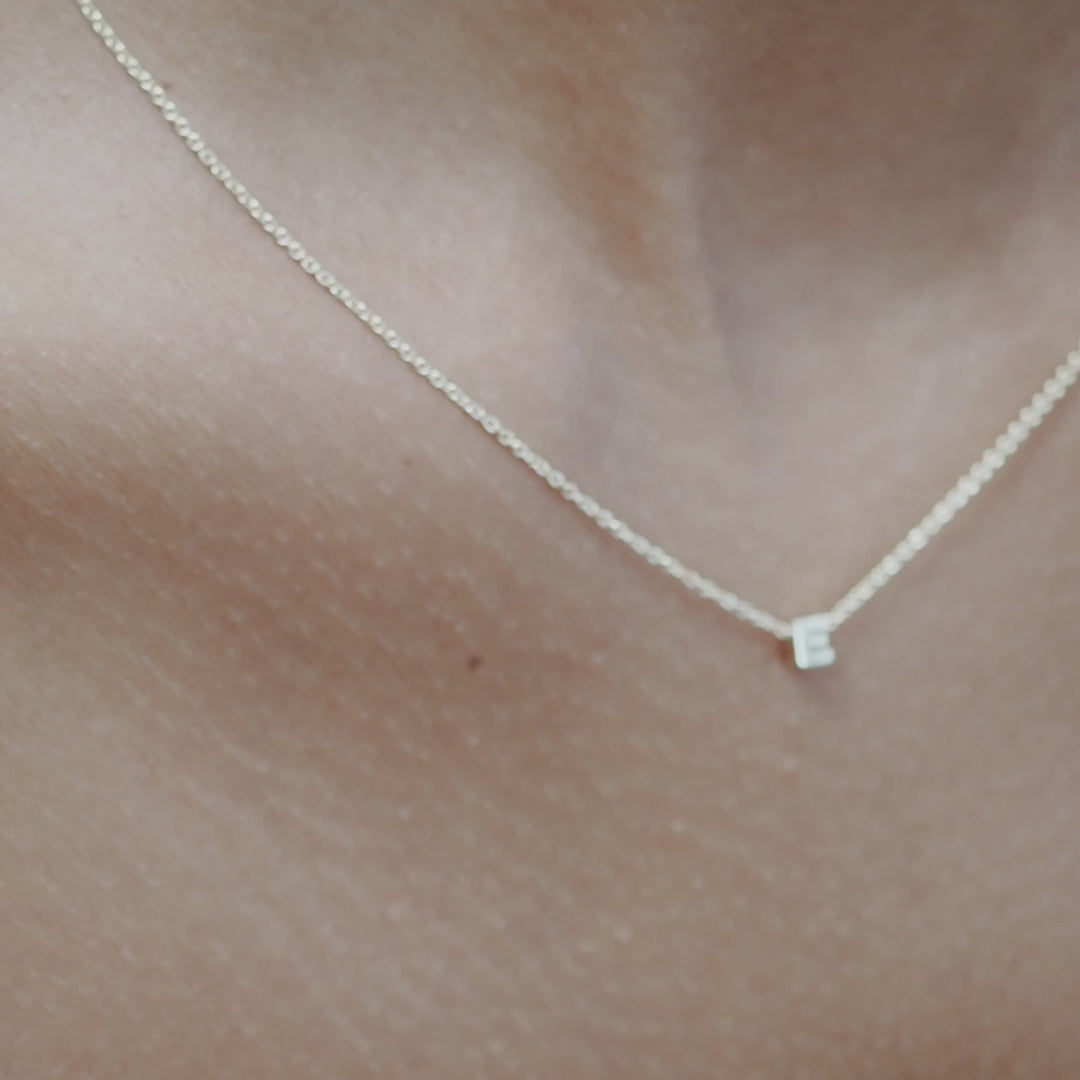 Solid gold and sterling silver jewellery: Video of a model wearing our signature sterling silver tiny letter E charm necklace on a 40cm cable chain