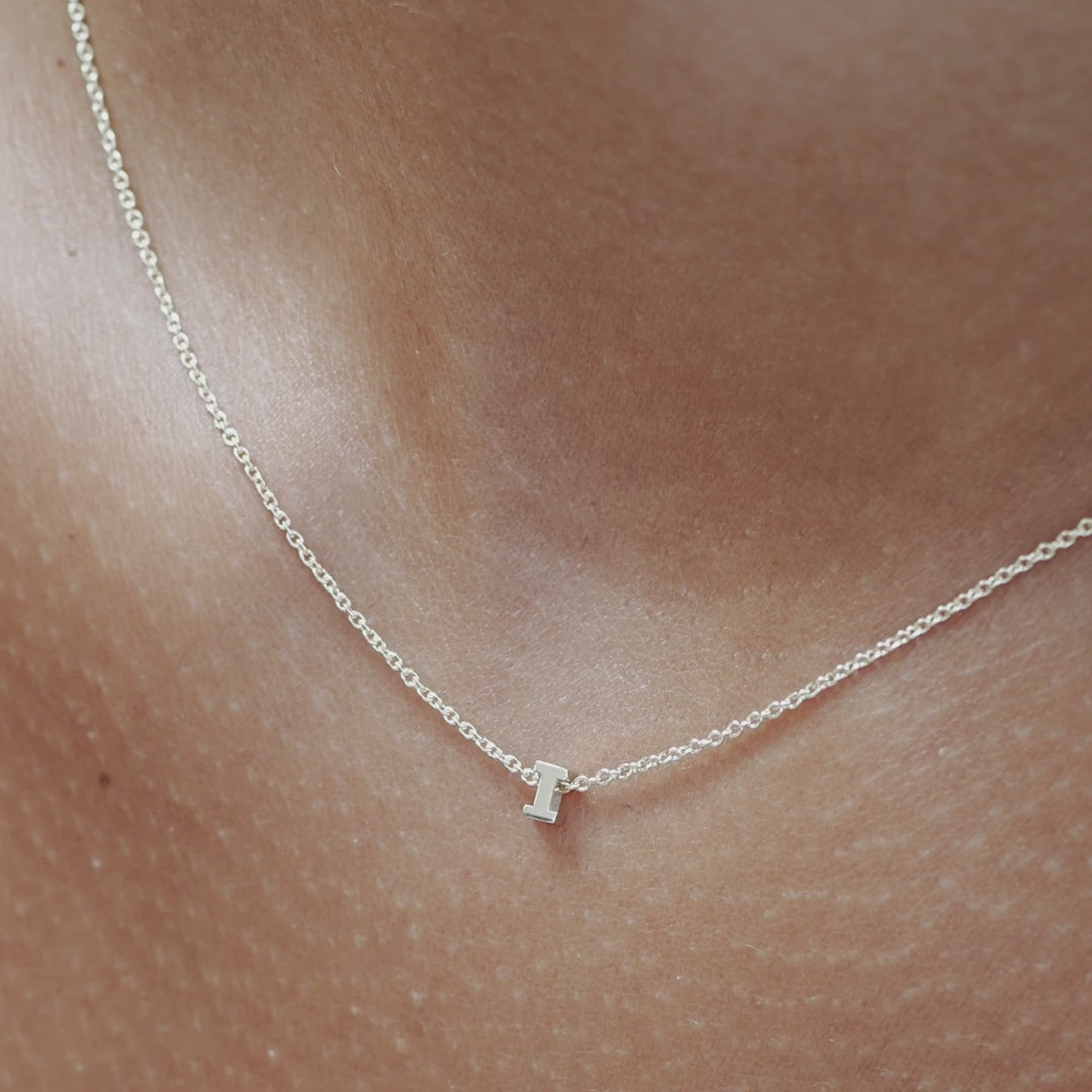 Solid gold and sterling silver jewellery: Close up video of a model wearing our signature sterling silver Tiny Letter I Charm Necklace on a 40cm cable chain