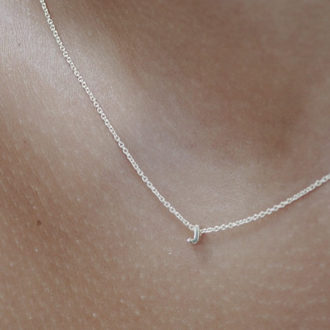 Solid gold and sterling silver jewellery: Close up video of a model wearing our signature sterling silver Tiny Letter J Charm Necklace on a 40cm cable chain