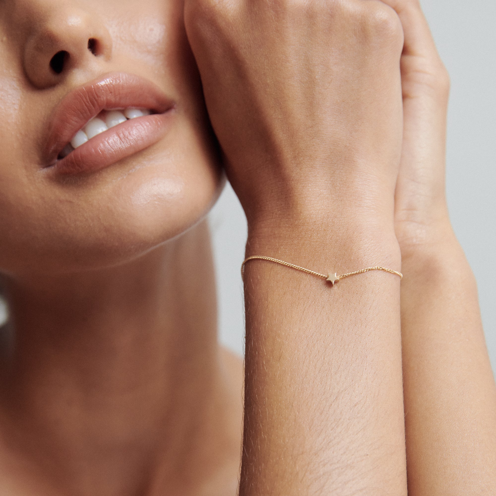 Woman's wrist adorned with a delicate gold chain bracelet, showcasing minimalist luxury jewellery against soft skin tones.