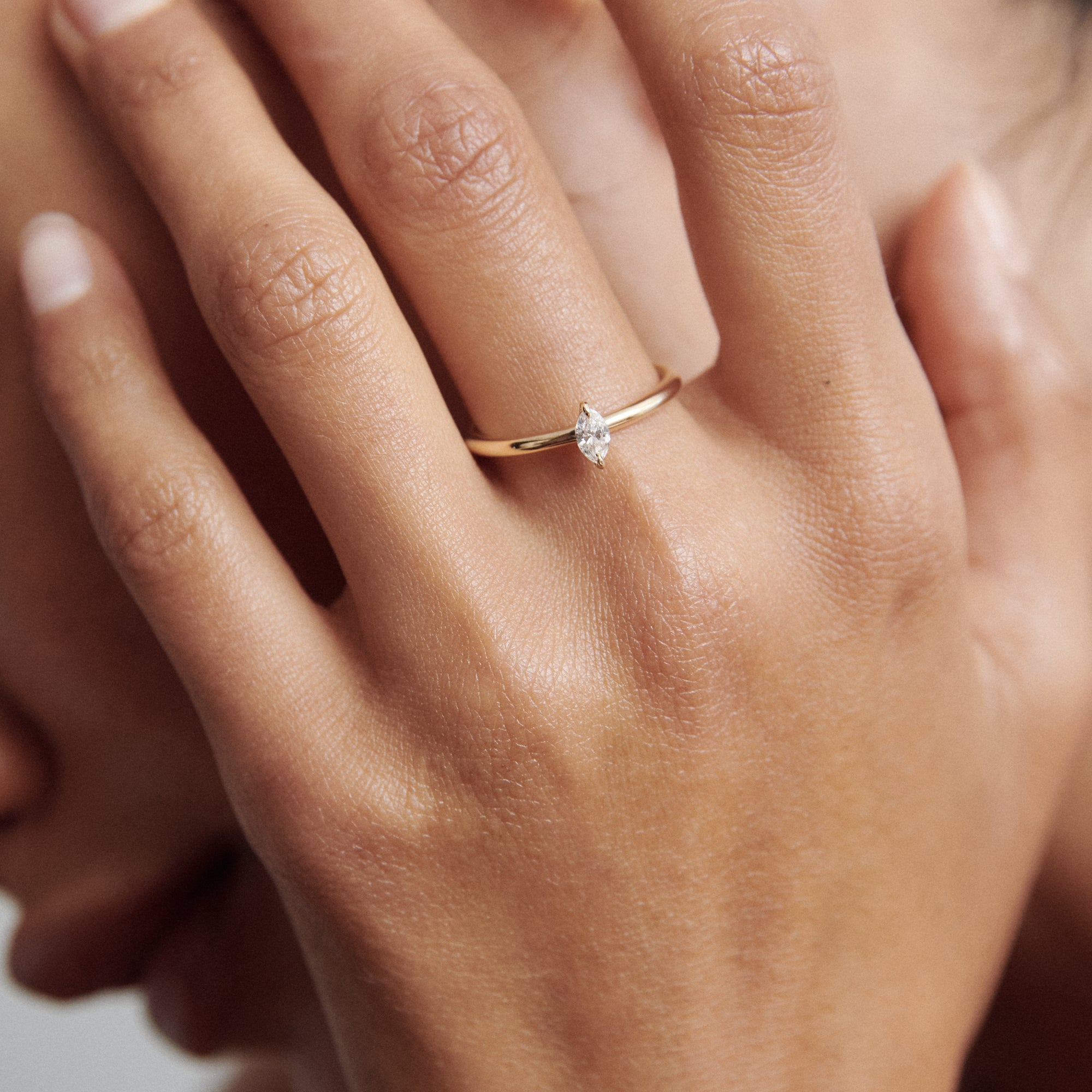 A delicate gold ring with a marquise diamond adorning a woman's finger, showcasing luxury jewellery elegance.