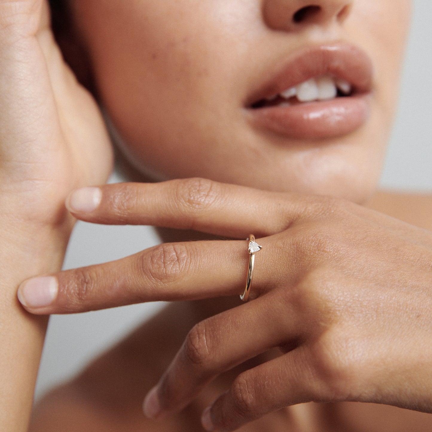 Close-up of a woman's hand showcasing a delicate gold ring with a teardrop diamond, capturing luxury jewellery details.