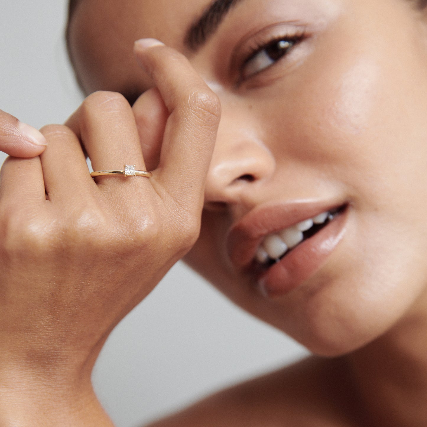Woman wearing an elegant gold diamond ring, showcasing luxury jewellery. Natural makeup and soft focus highlight the ring's brilliance.