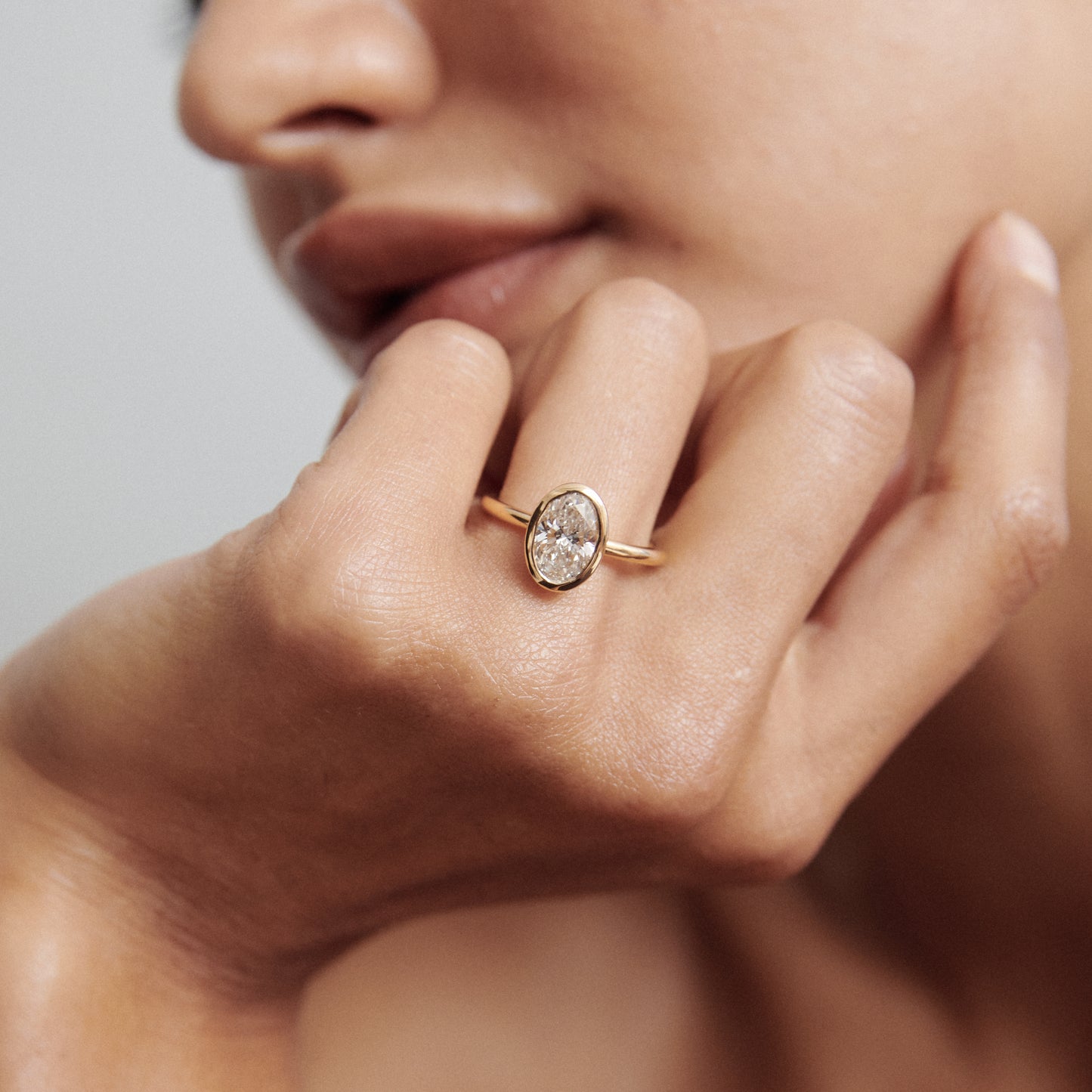 Elegant gold ring with large oval gemstone, worn on a woman's hand. Luxurious jewellery close-up.