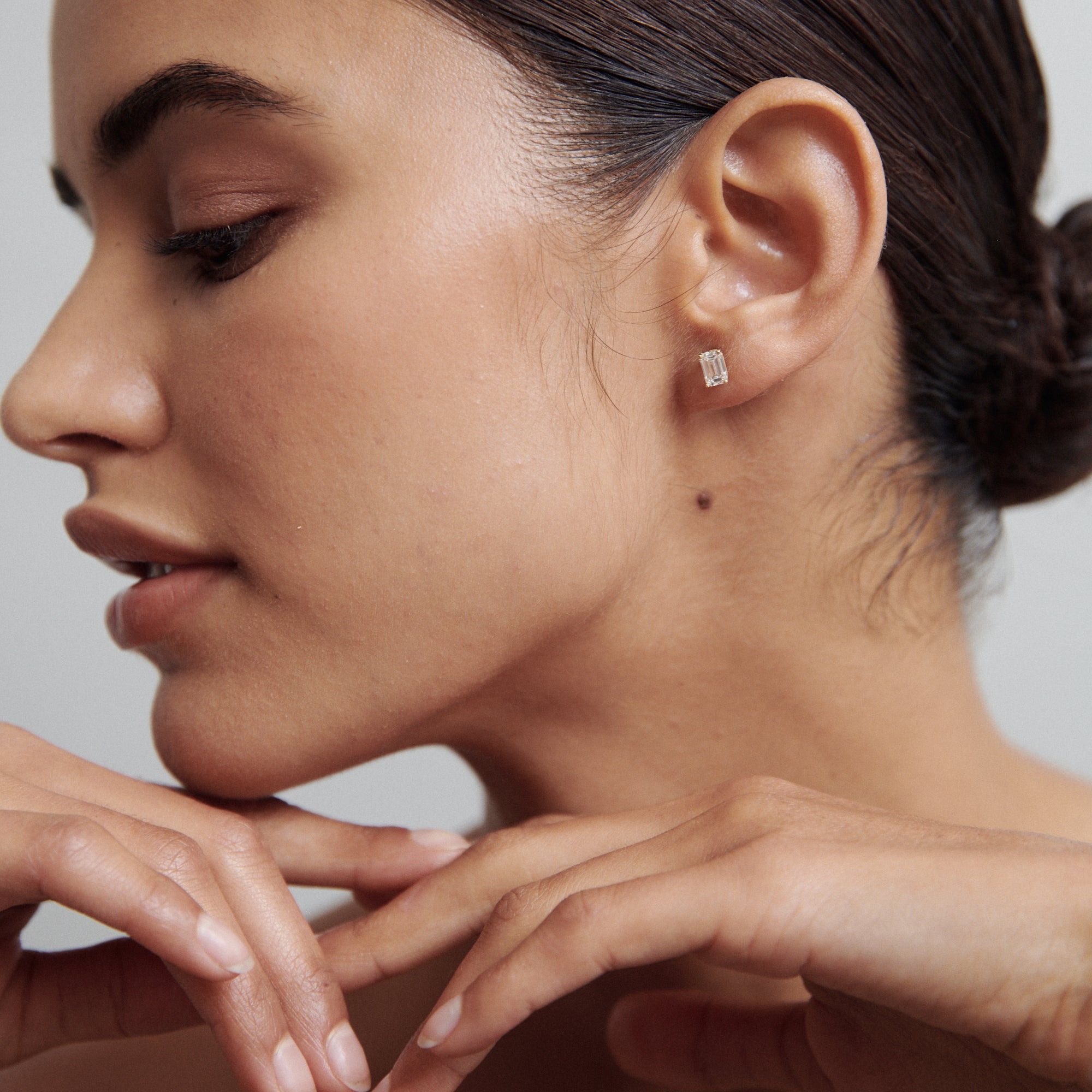 Woman with sleek hair wearing elegant rectangular diamond stud earrings, showcasing minimalistic luxury jewellery. Side profile view.