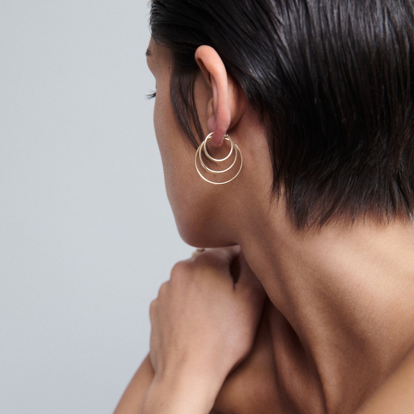 Woman with short hair wearing elegant gold hoop earrings.