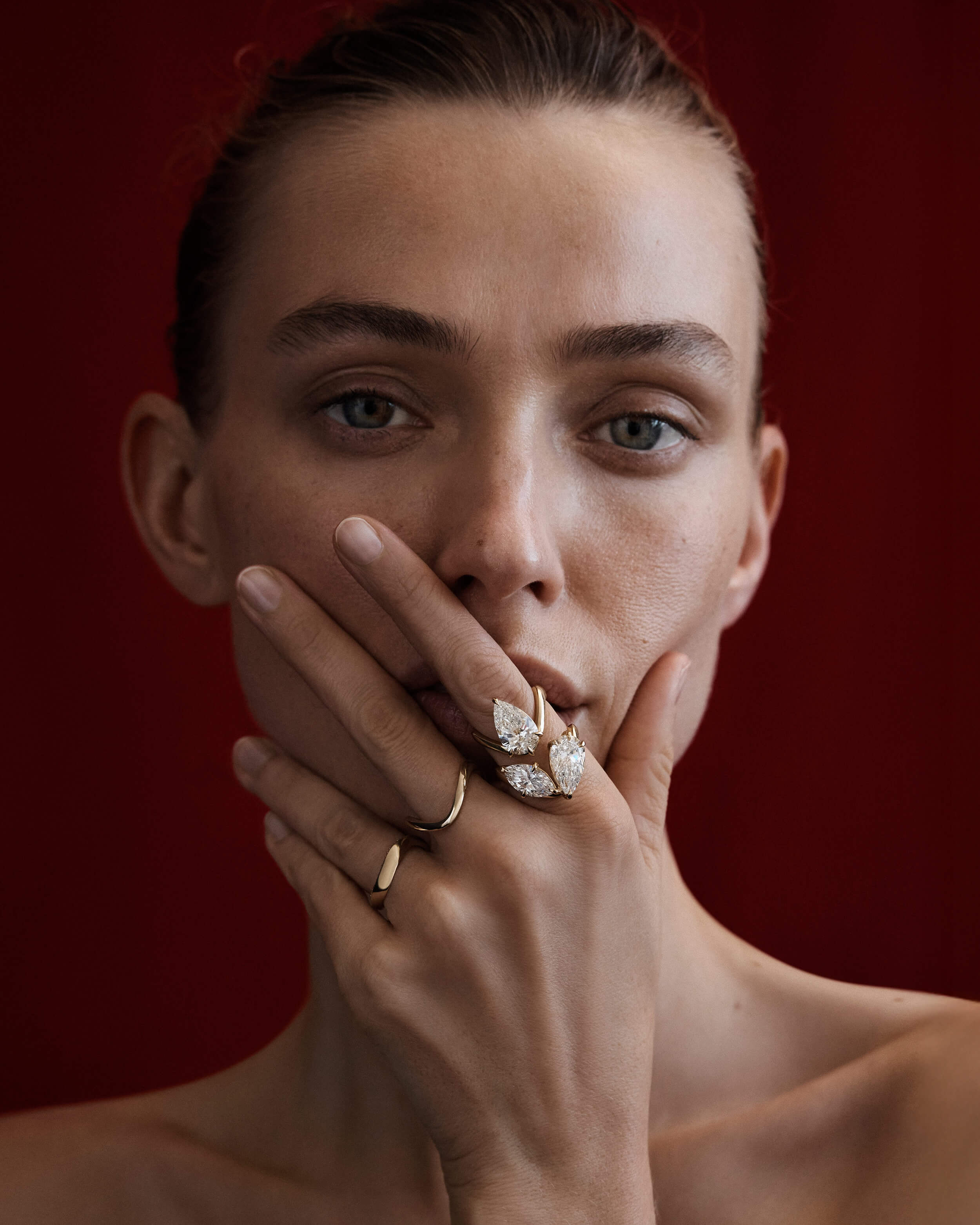 Woman wearing multiple rings on a red background