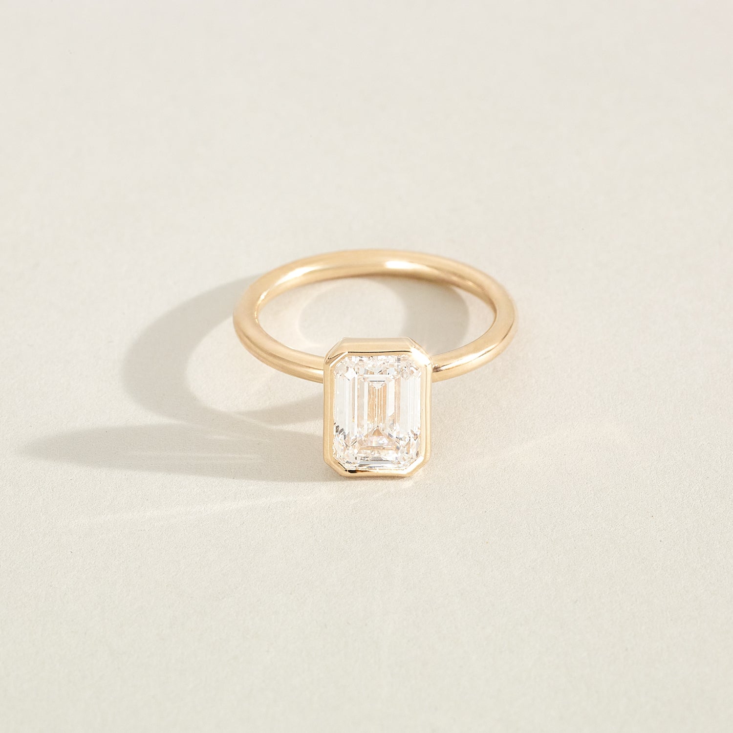 Gold ring with a rectangular diamond on a light beige background