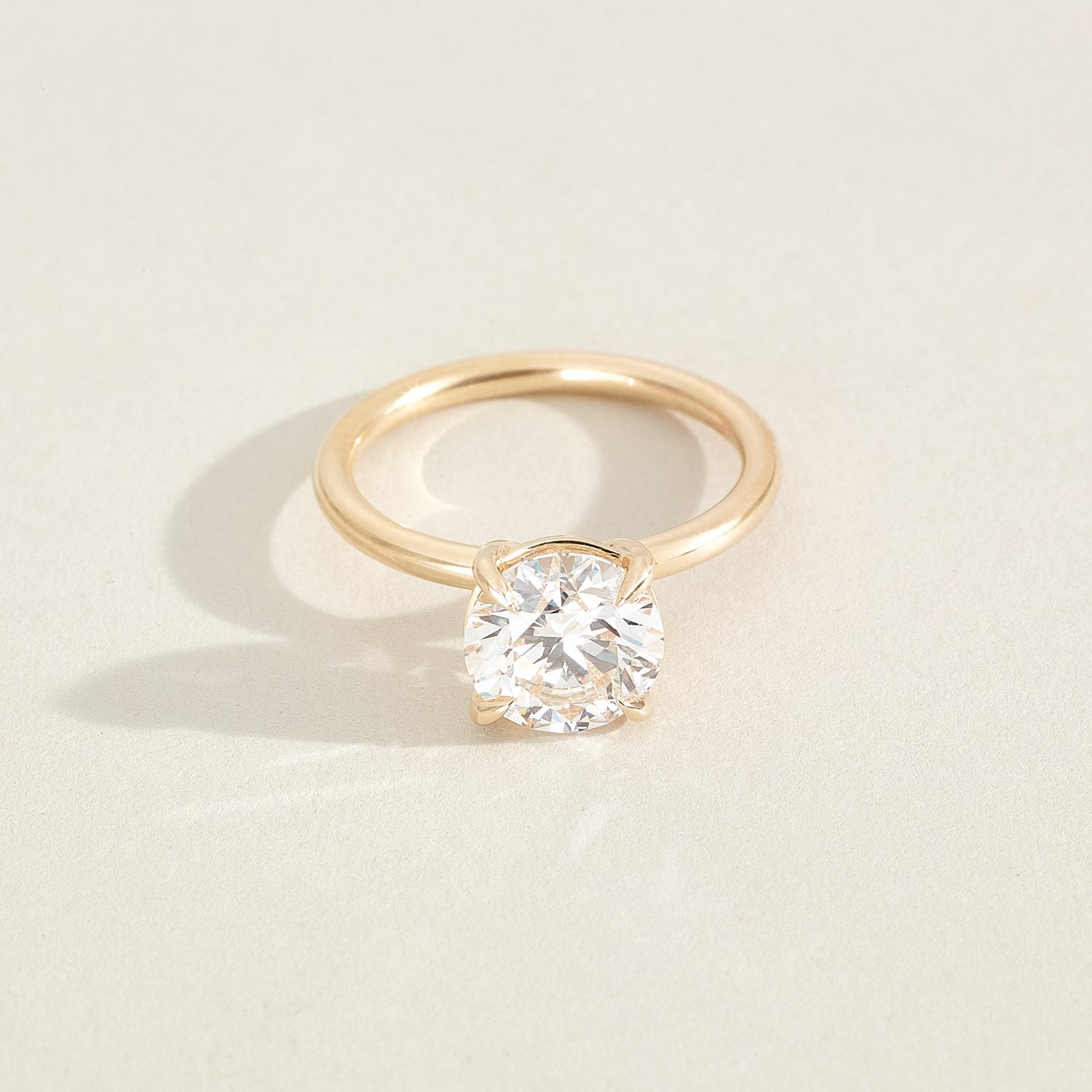 Gold ring with a diamond on a light beige background