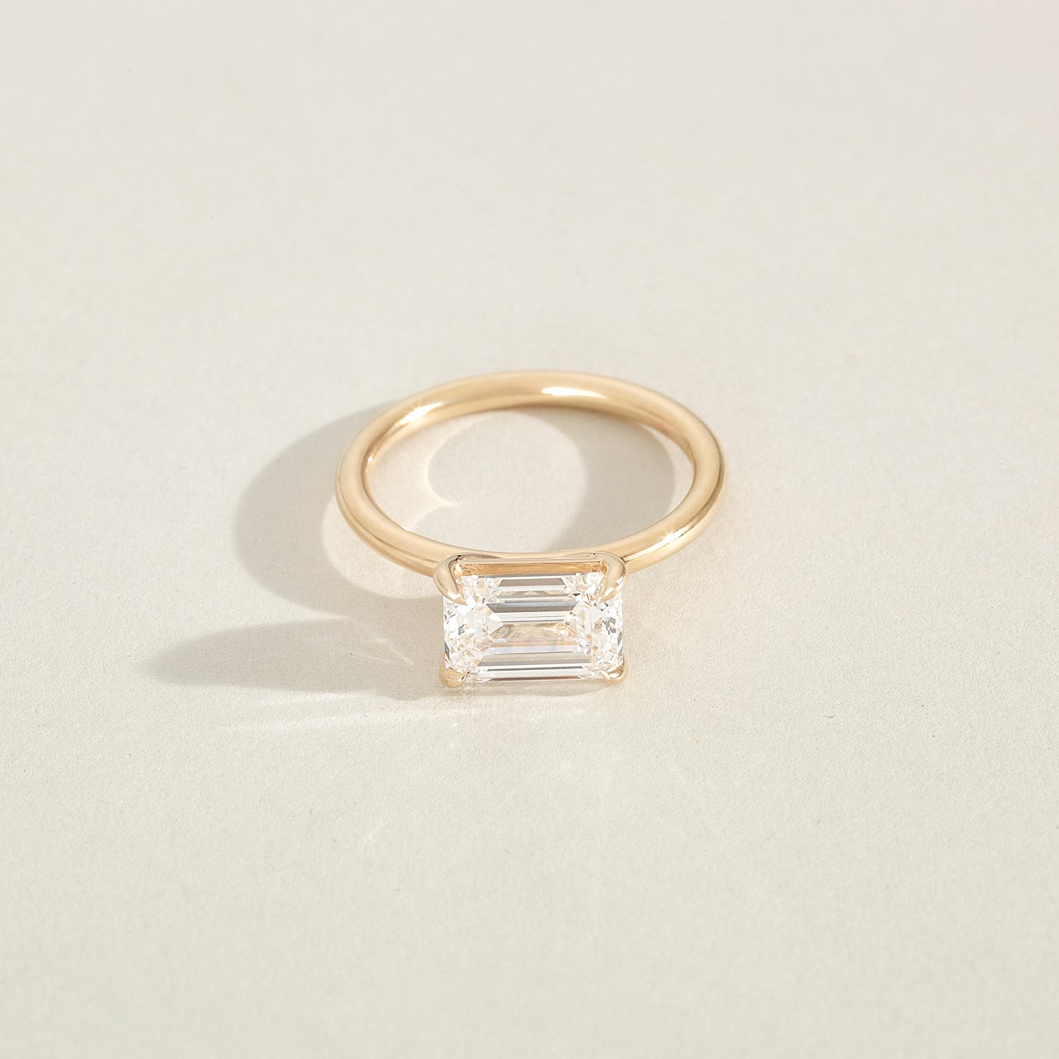 Gold ring with a rectangular diamond on a beige background