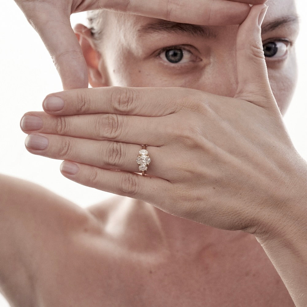 Woman framing her face with hands, showcasing an elegant diamond ring on her finger. High-end jewellery, luxury style.