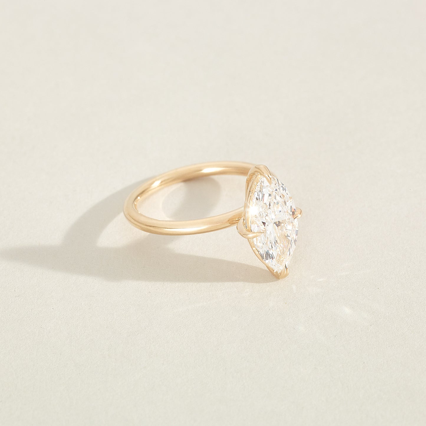 Gold ring with a pear-shaped diamond on a light beige background