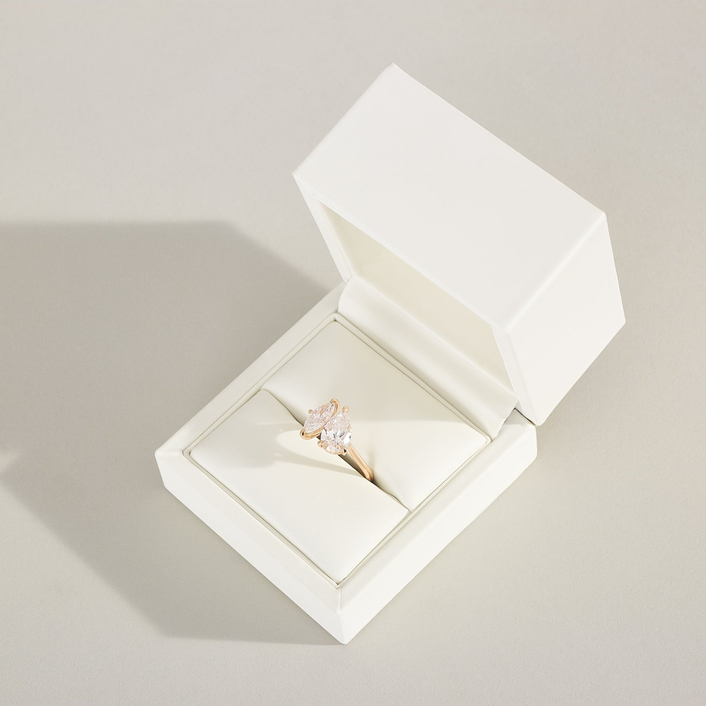 Diamond ring in an open white jewelry box on a light gray background