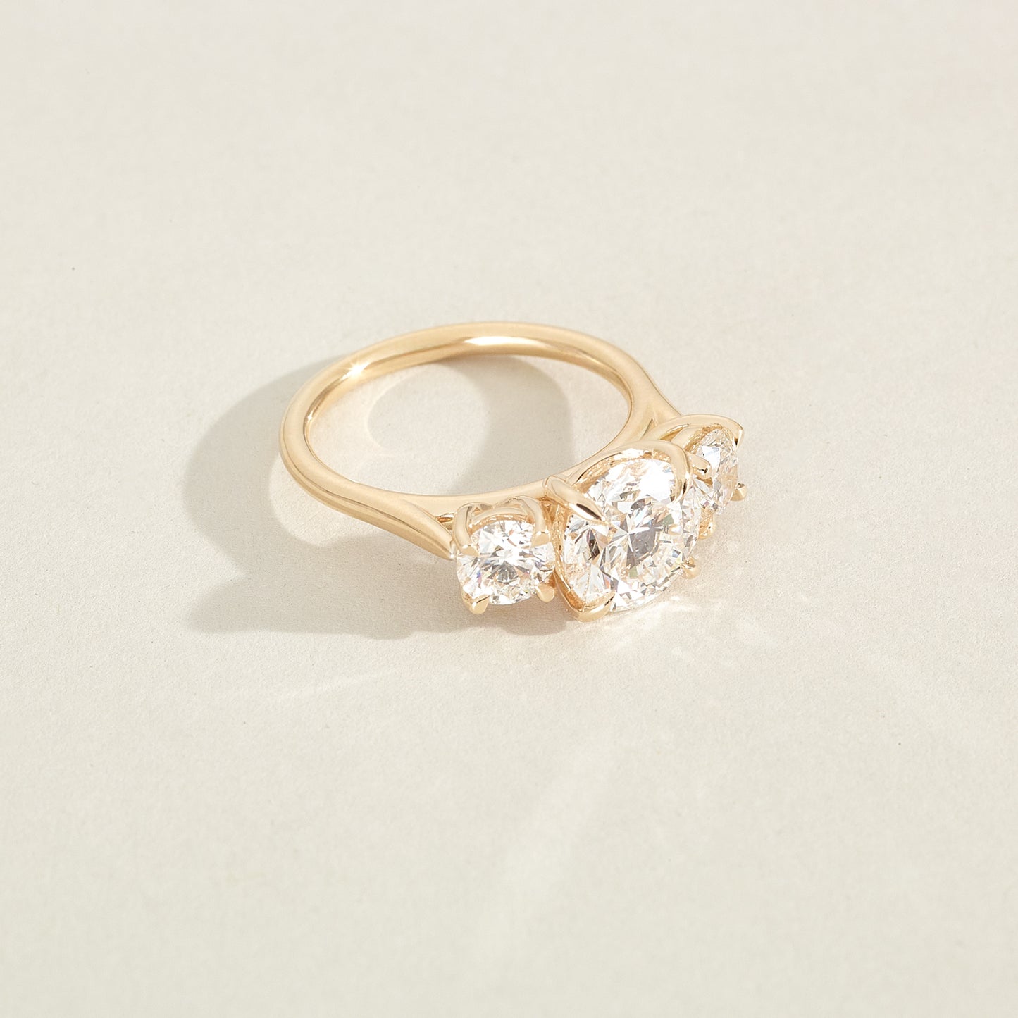 Gold ring with two diamonds on a beige background