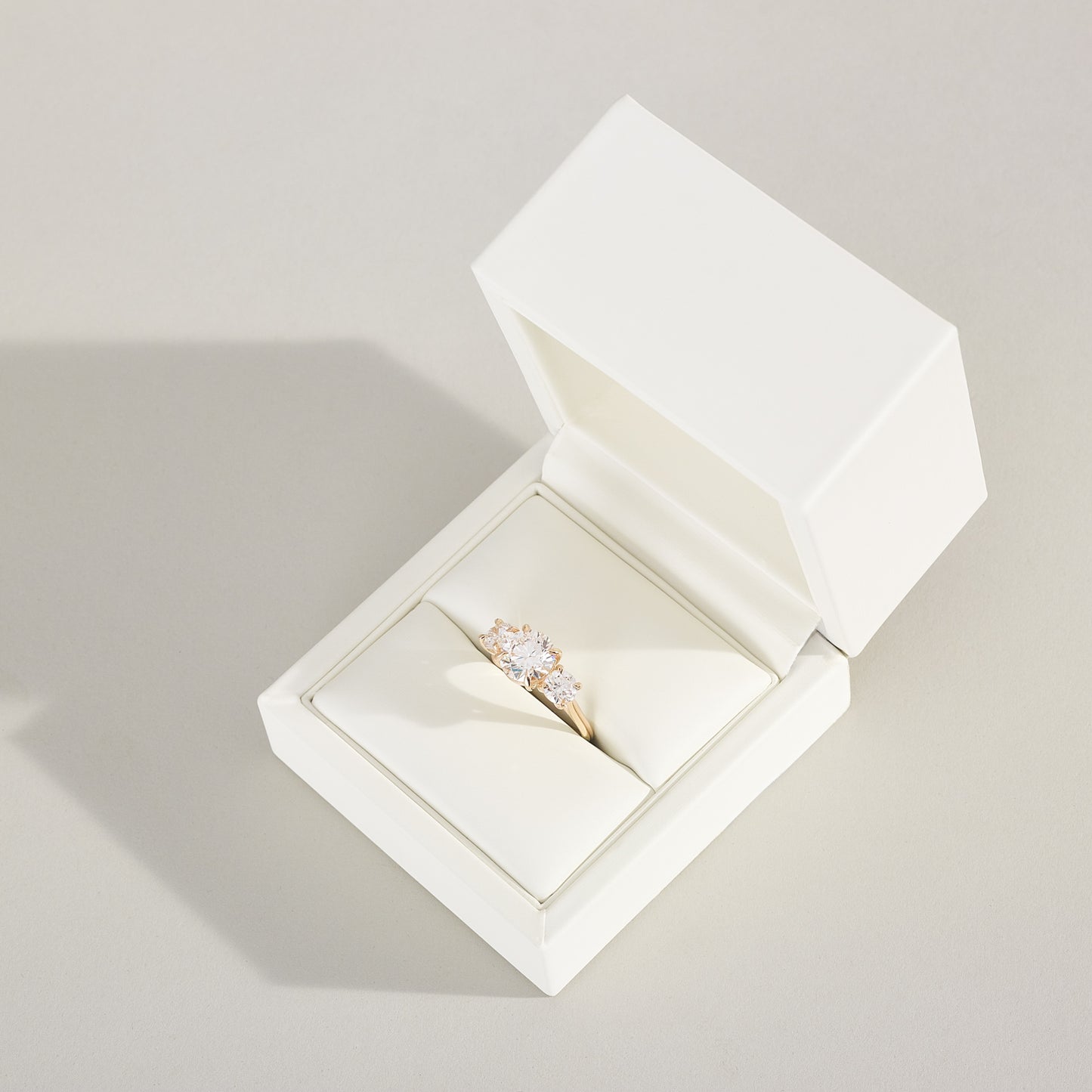 Open white jewelry box with a ring inside on a light gray background