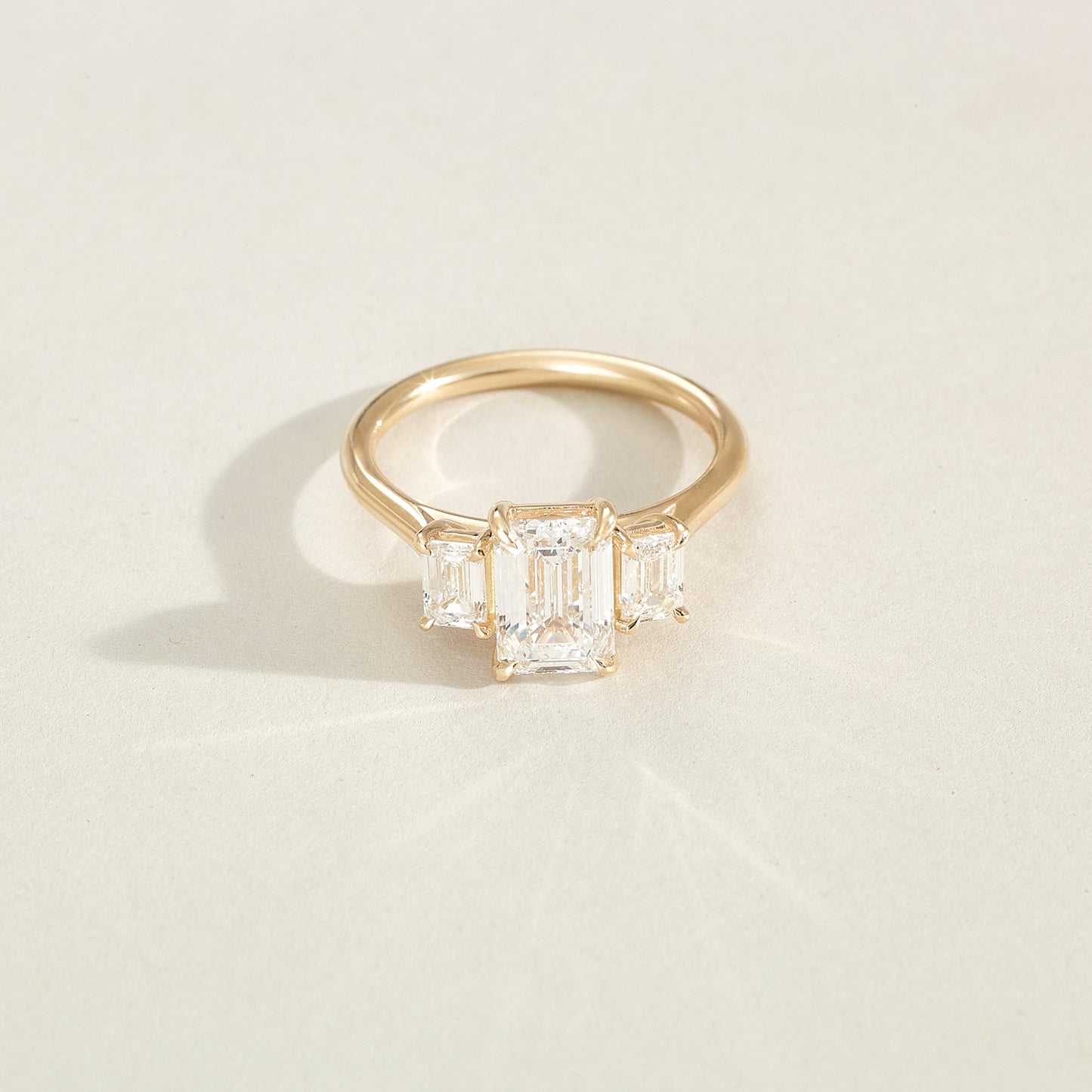 Gold ring with three diamond stones on a light beige background