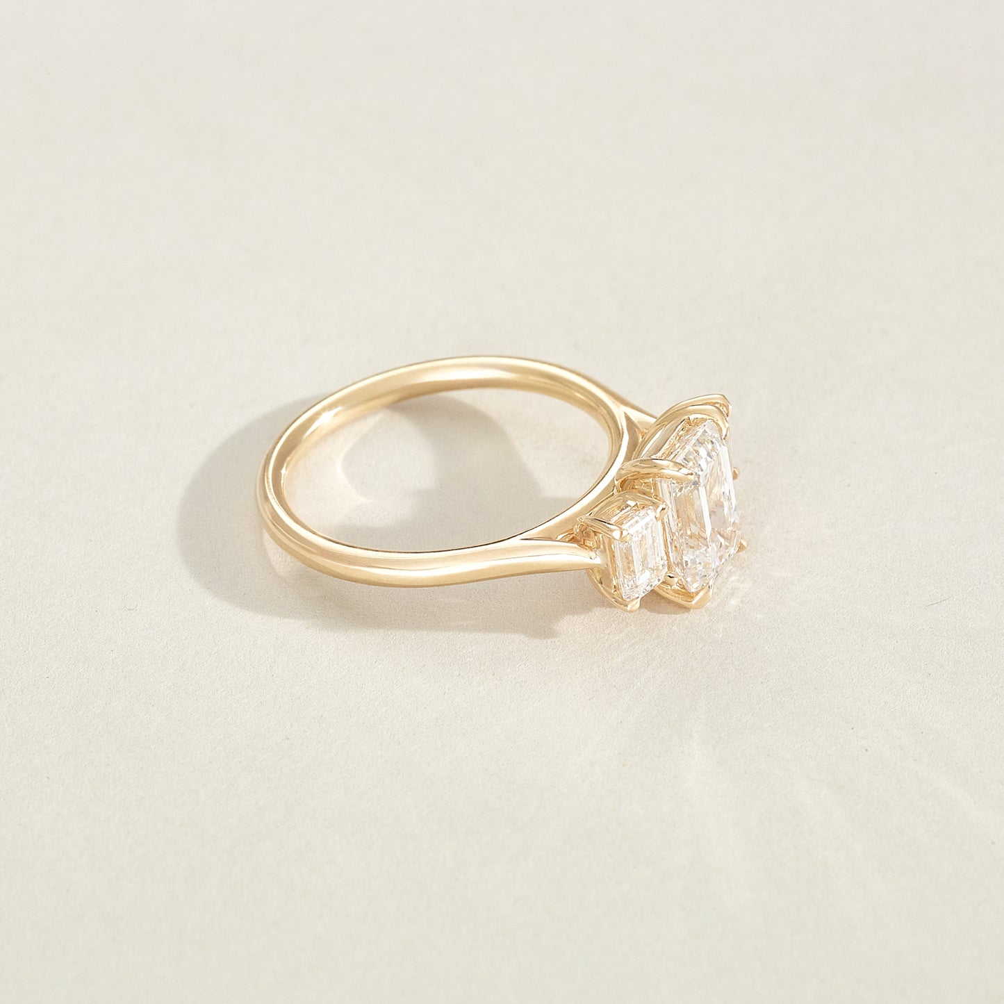 Gold ring with a diamond on a light beige background
