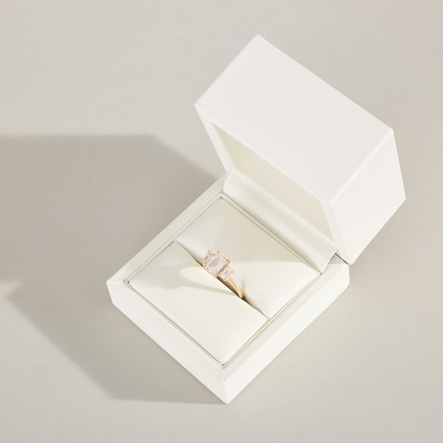 Open white jewelry box with a ring inside on a light gray background