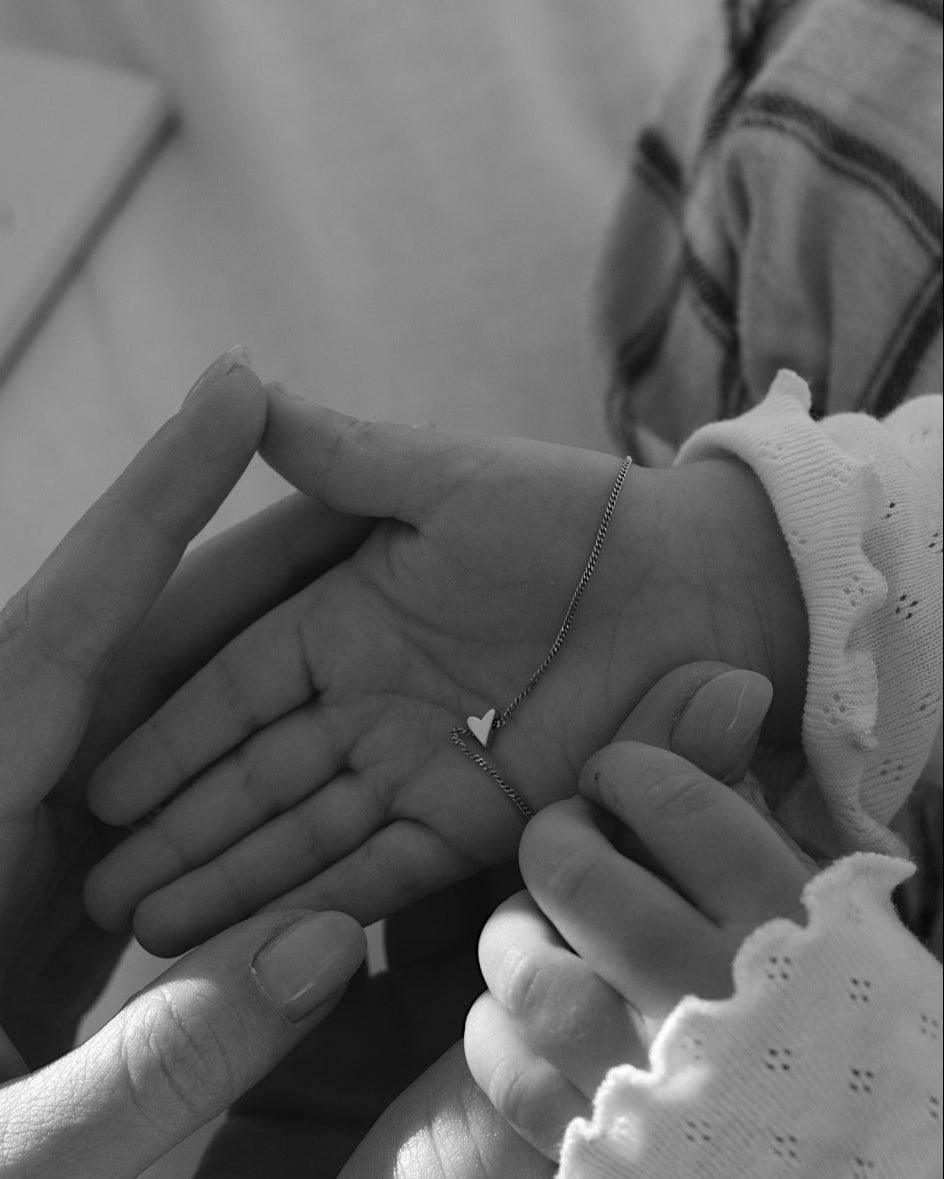 Black and white photo of two pairs of hands holding a baby's hand.