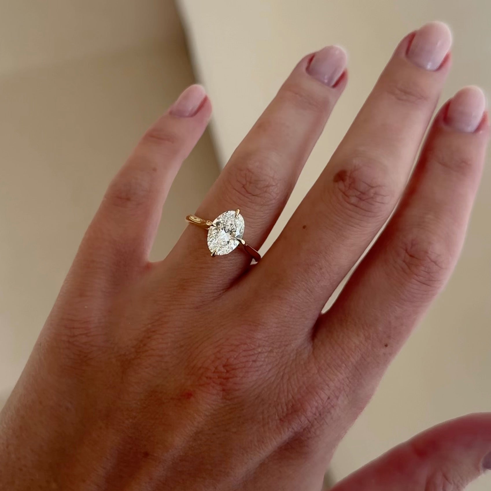 Elegant marquise-cut diamond ring on a hand, set in gold, showcasing luxury jewellery design with simple, polished nails.