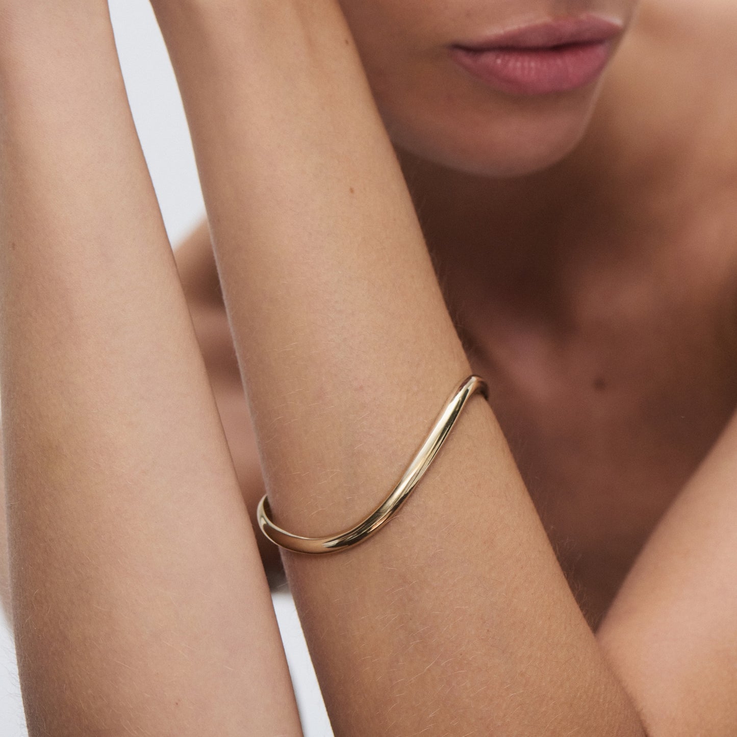 Elegant gold bangle on woman's wrist, highlighting luxury jewellery fashion with minimalist design.