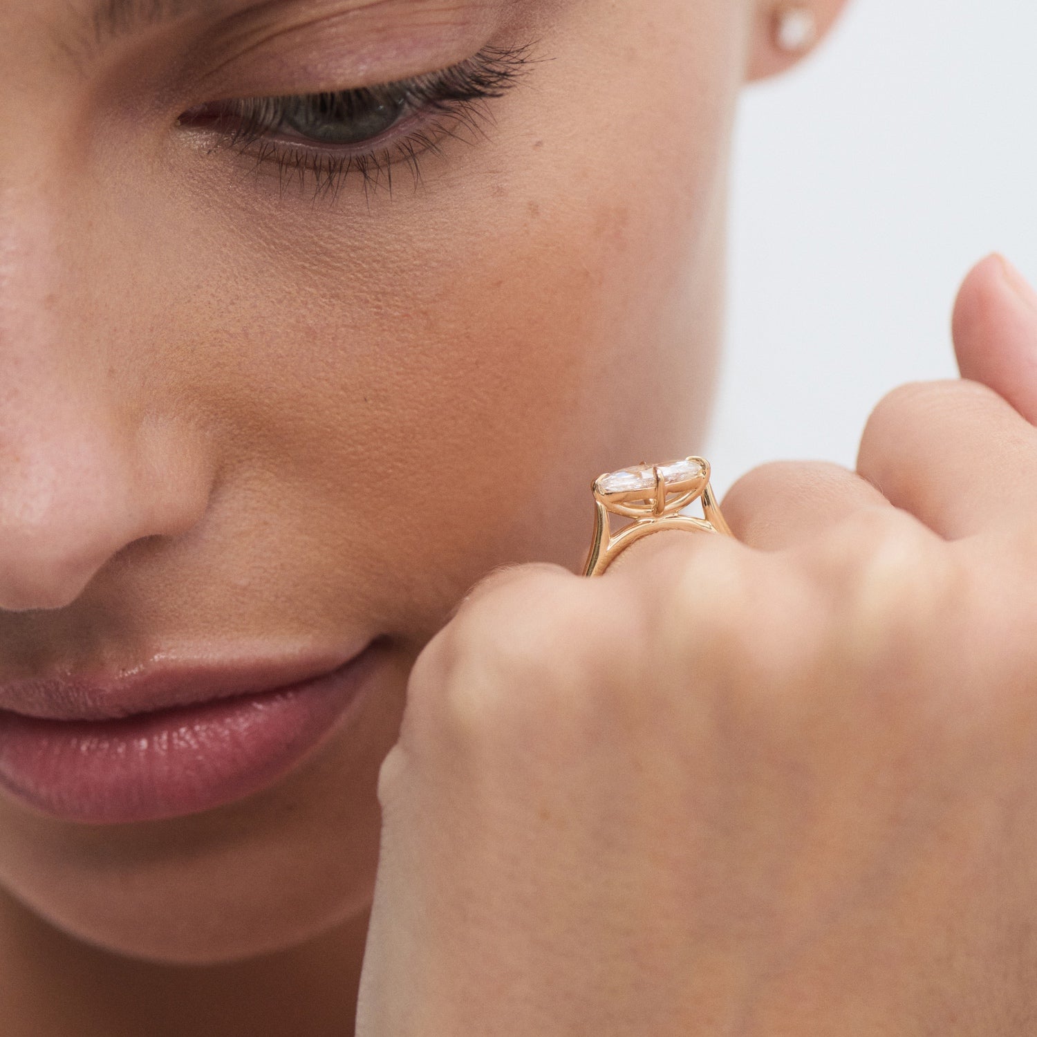 Close-up of a woman admiring her gold ring with a large gemstone, showcasing luxury jewellery and elegant design.