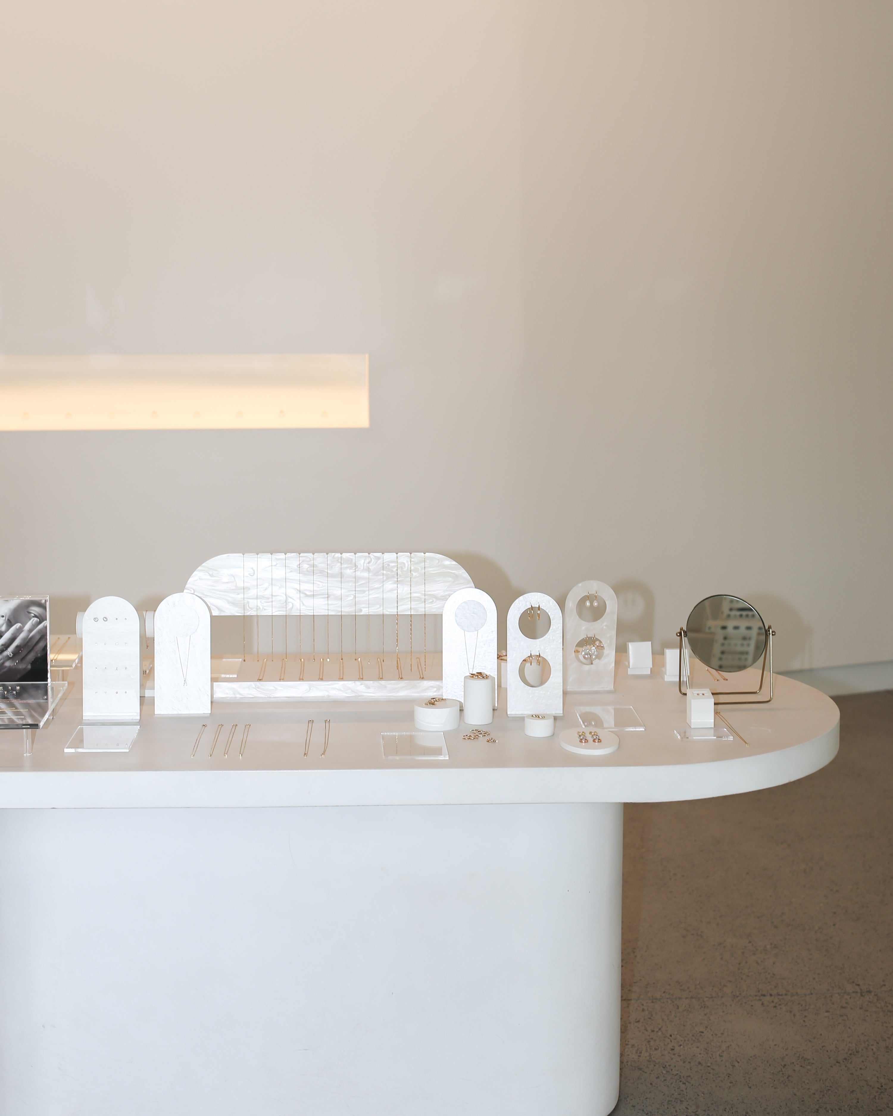 Minimalist jewellery display featuring gold and silver earrings and necklaces on a sleek white table in a luxury boutique setting.