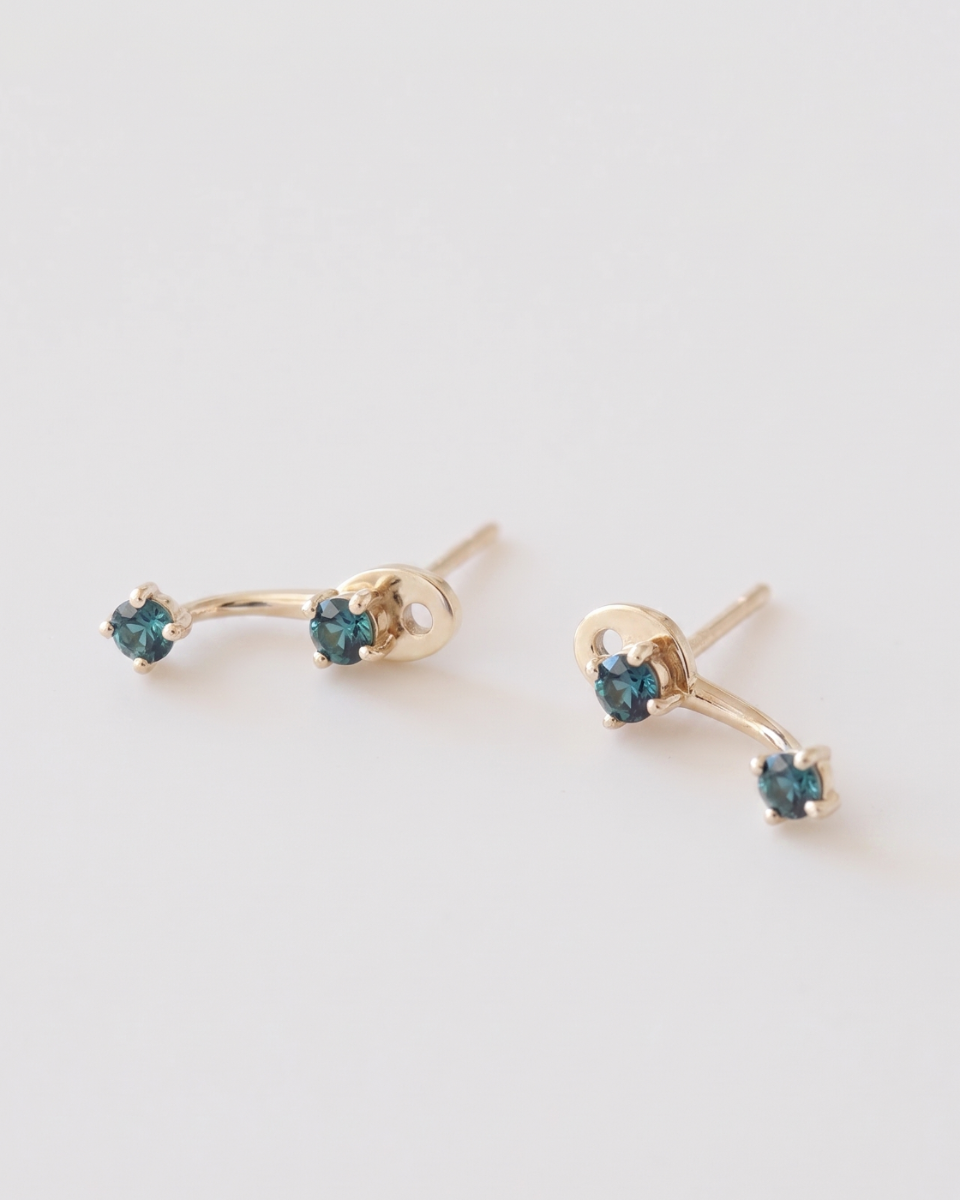 Gold earrings with blue gemstones on a white background