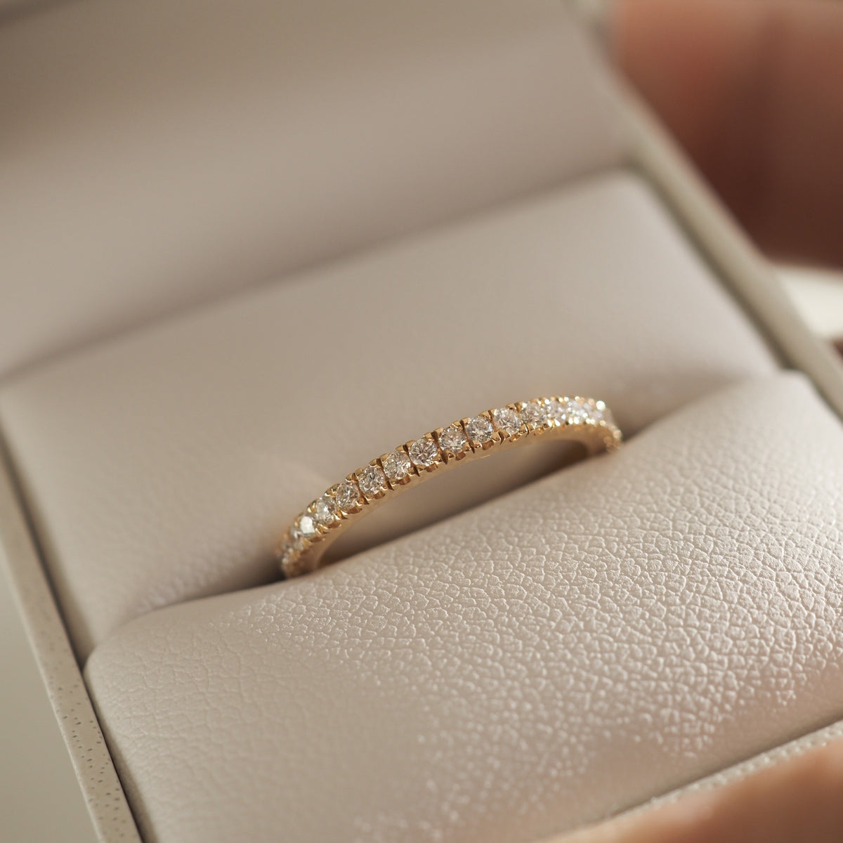 Elegant gold diamond eternity ring displayed in a plush jewellery box, showcasing timeless luxury and exquisite craftsmanship.