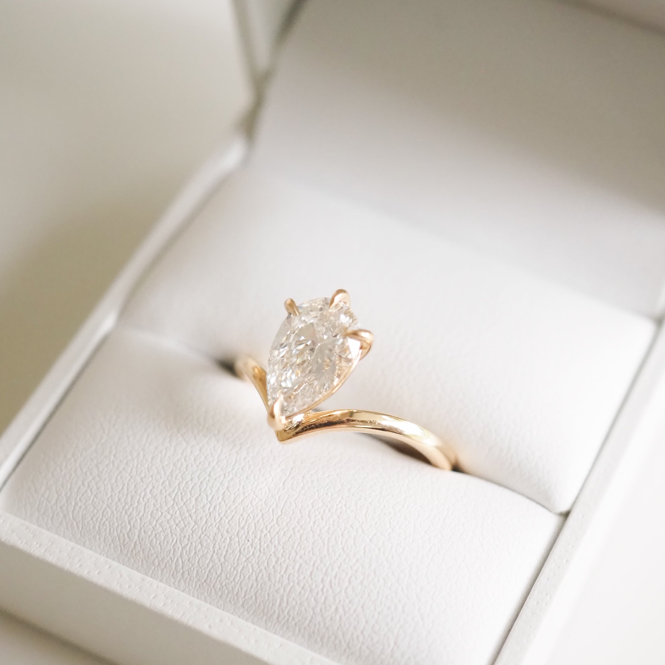 Elegant gold ring with a marquise diamond in a white jewellery box, accentuating luxury and sophistication.