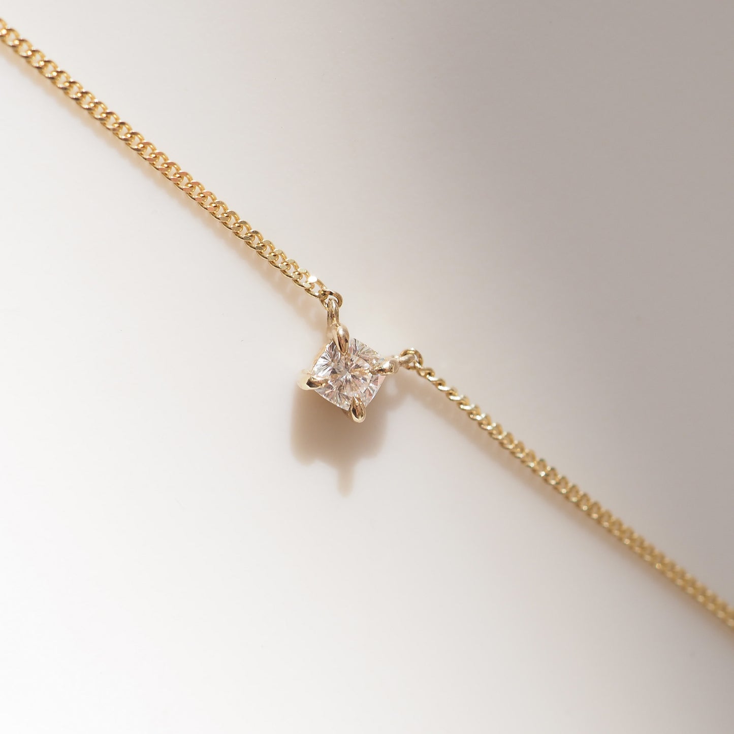 Gold necklace with a diamond pendant on a light background