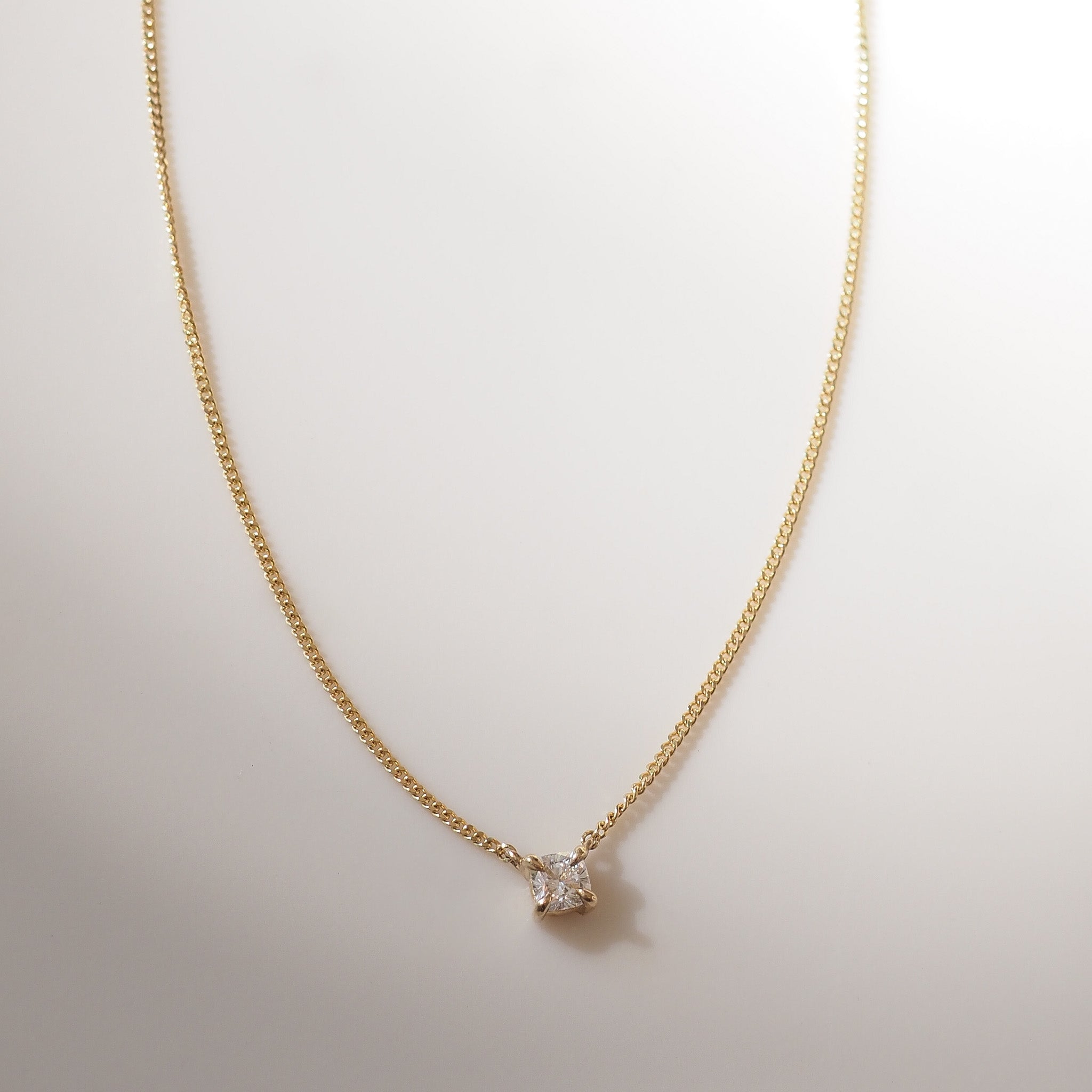 Gold necklace with a small diamond pendant on a light background