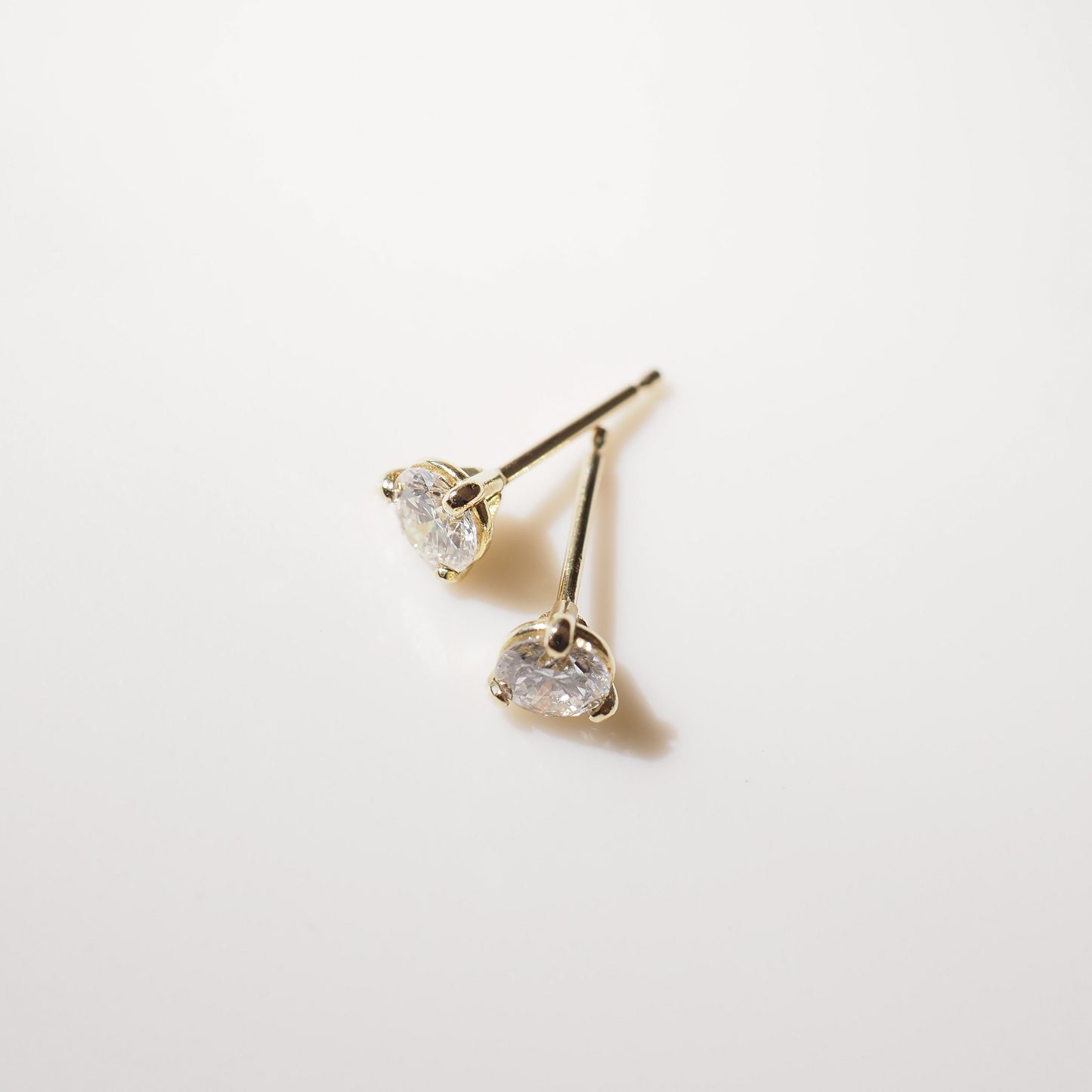 Gold heart-shaped earrings on a light gray background